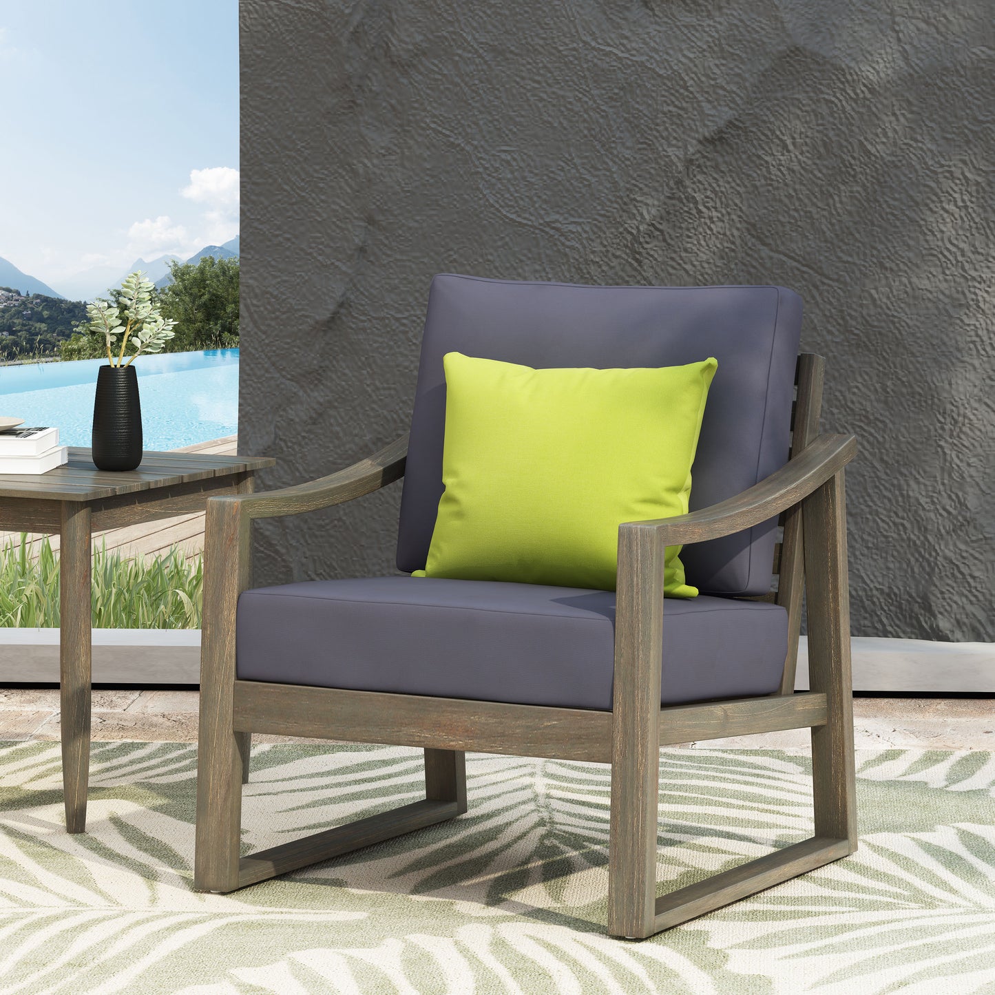 Gray upholstered wooden outdoor armchair with a lime green accent pillow on a patio