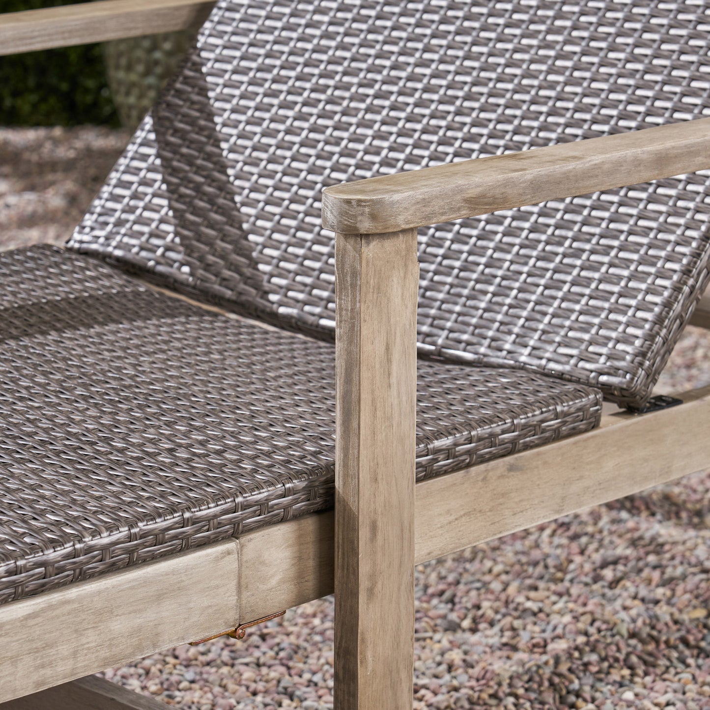 Closeup of a grey wicker outdoor chair with wooden armrests and frame