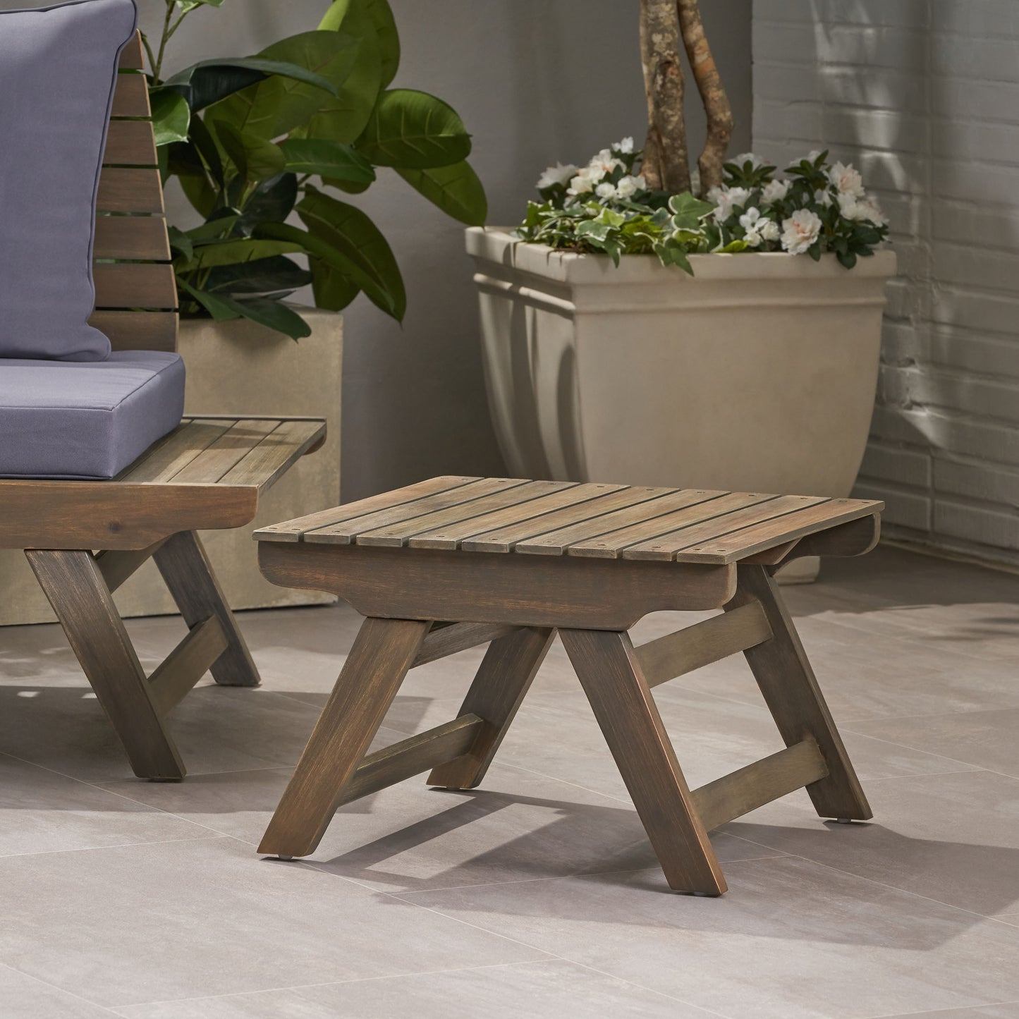 Brown slatted wood outdoor end table with angled legs on a patio