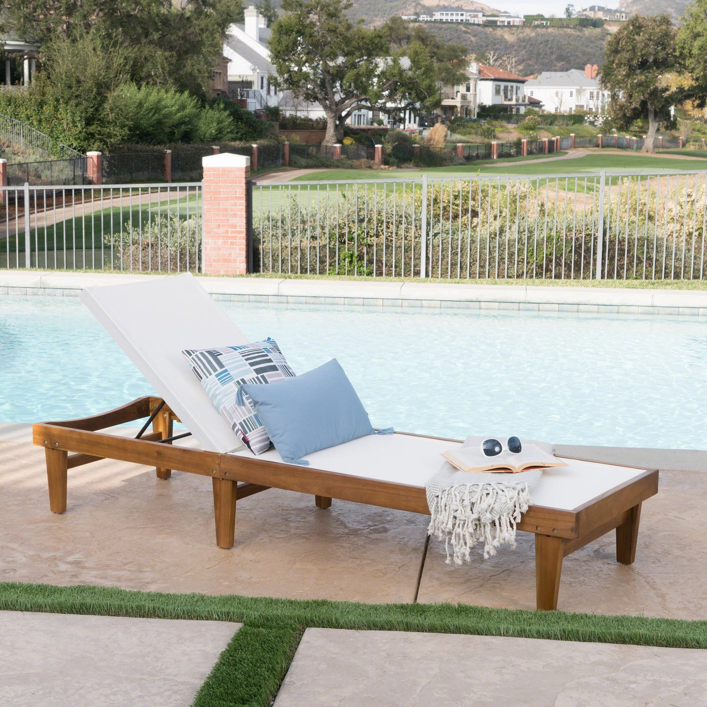 Wooden outdoor chaise lounge with white cushion blue and geometric pillows