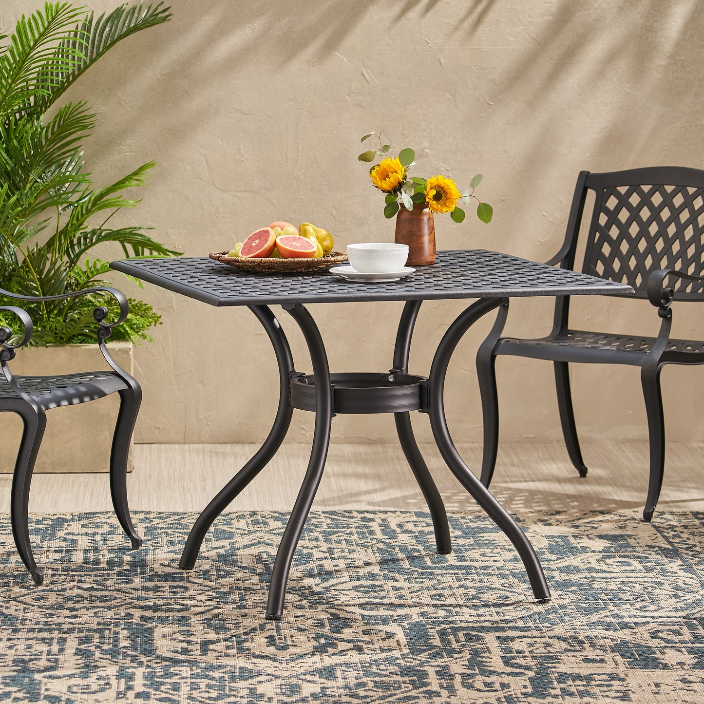 Black cast aluminum outdoor patio dining table with ornate legs and lattice top