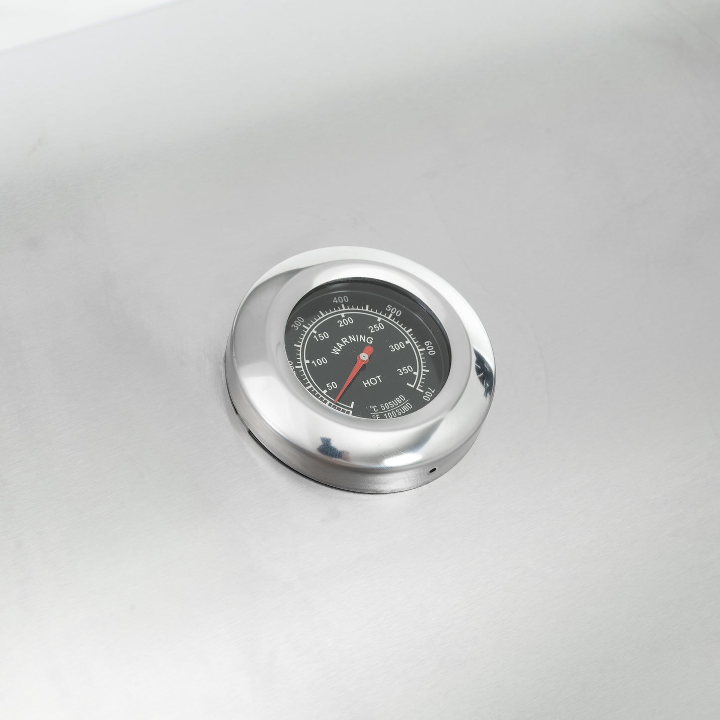 Round stainless steel thermometer dial with red indicator needle showing HOT