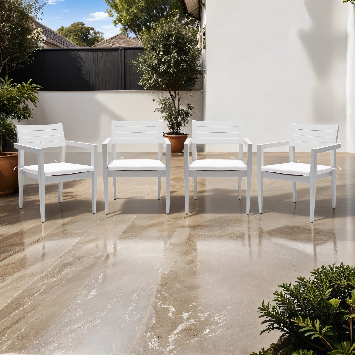 Four white modern outdoor armchairs with plush cushions on a marble patio