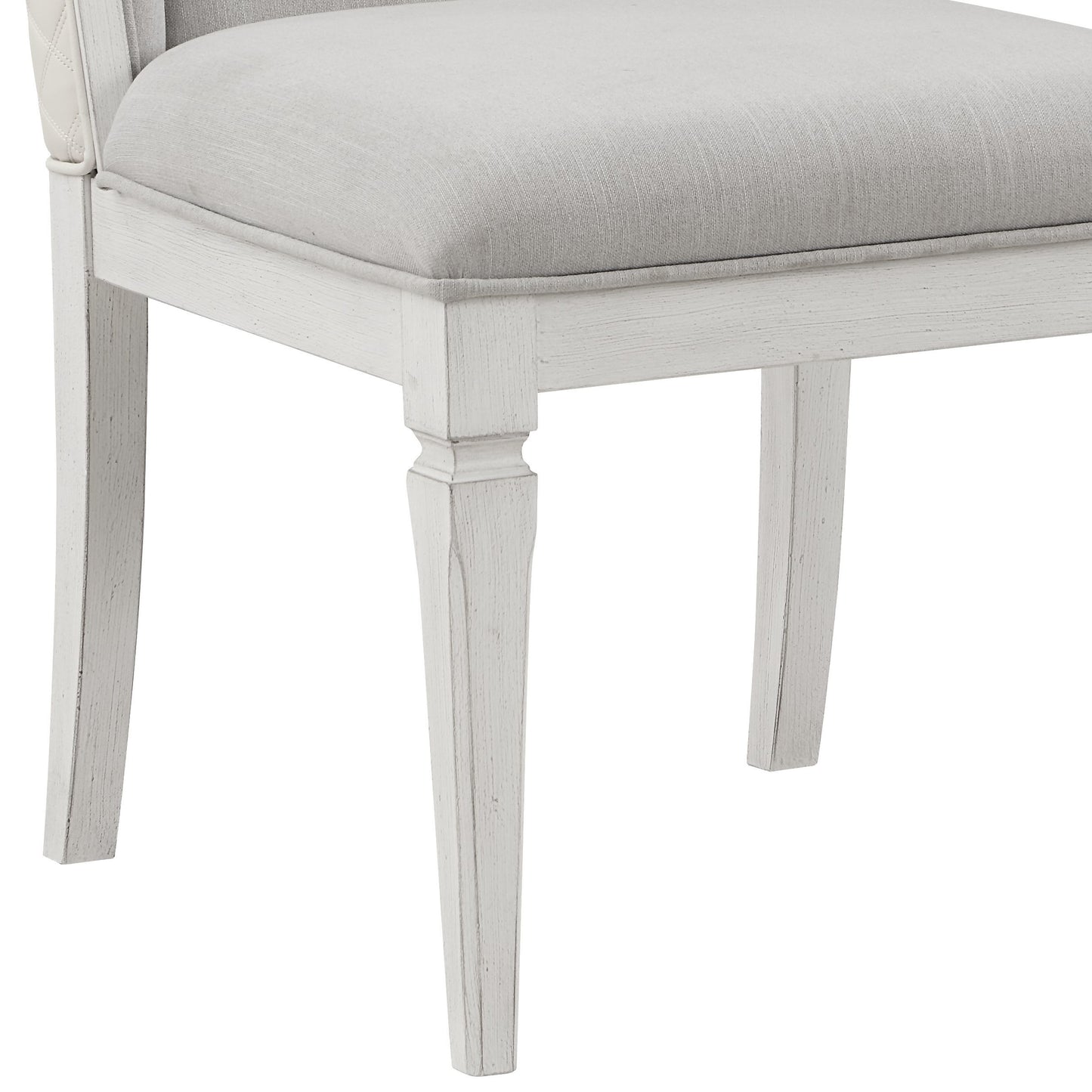 Closeup of a tufted white leather armchair armrest with a light grey linen seat cushion
