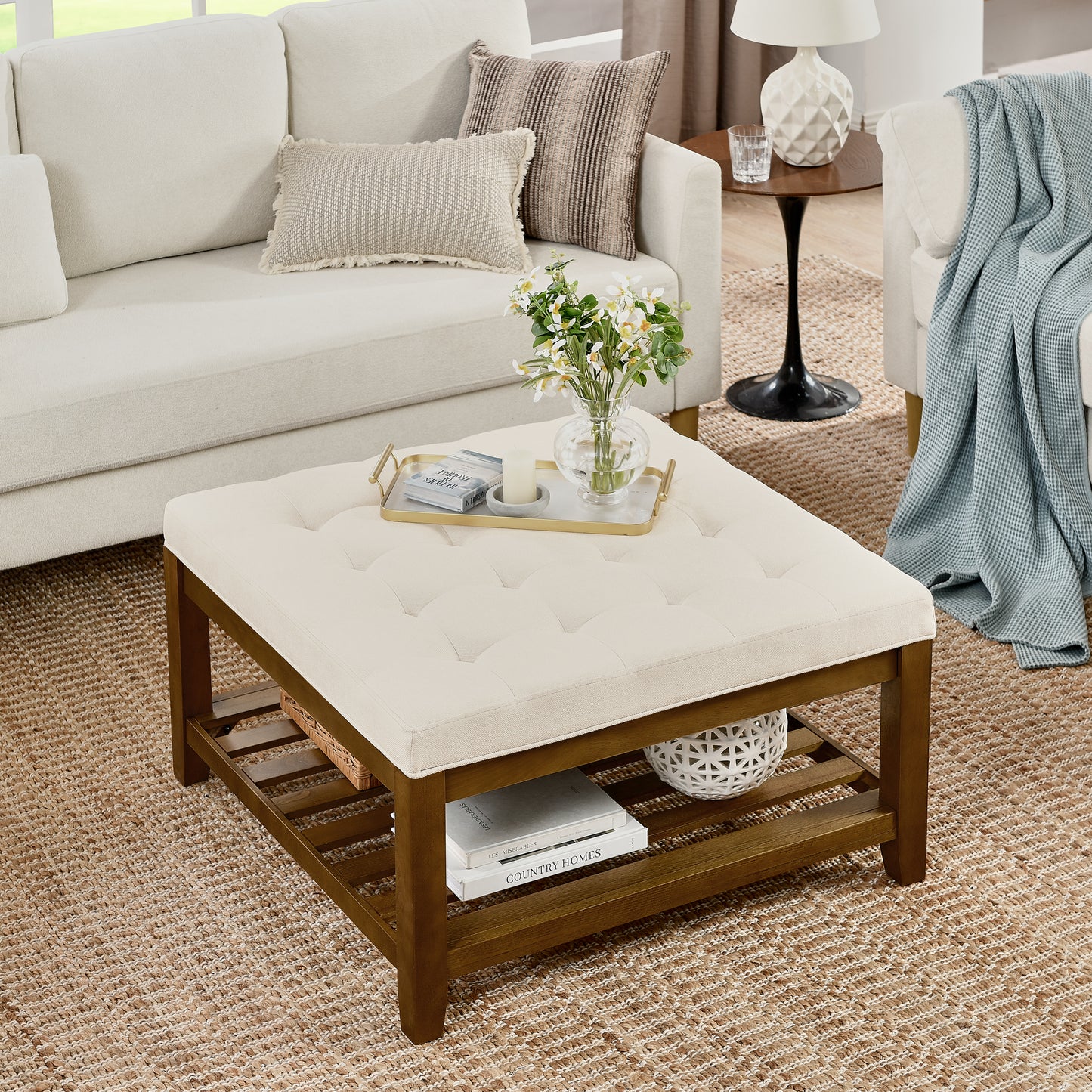 Tufted cream fabric storage ottoman with dark wood frame and slatted shelf