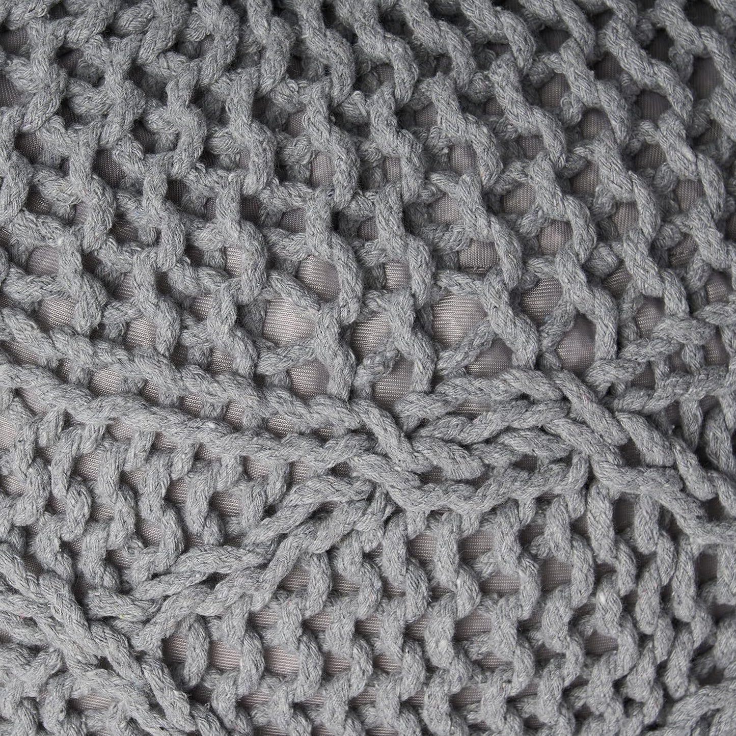Closeup of a chunky knit grey pouf with a macramestyle weave and visible texture