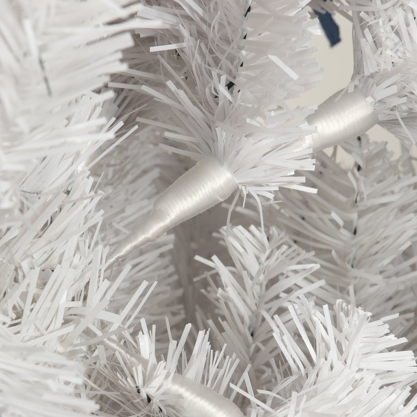 Closeup of white artificial Christmas tree needles with sparkling lights integrated