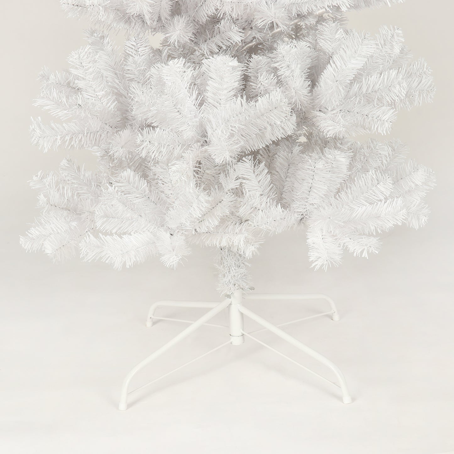 Close up of a fluffy white artificial Christmas tree with a metal stand
