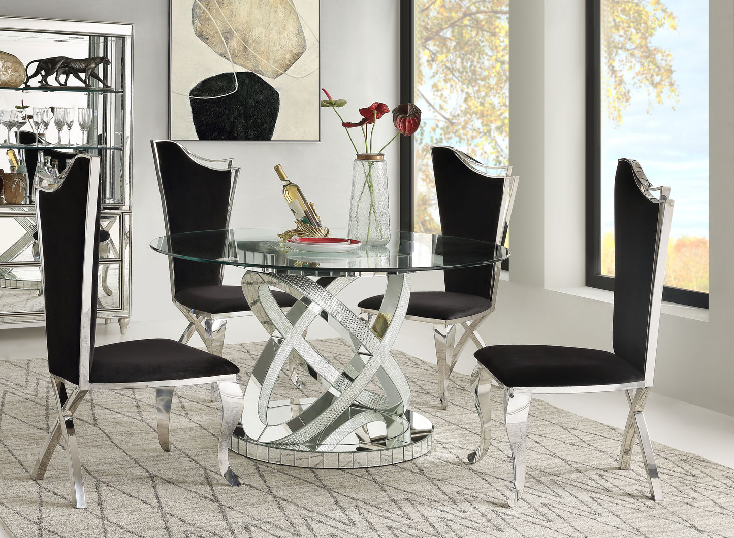 Round glass dining table with chrome and mirrored base and four black velvet chairs
