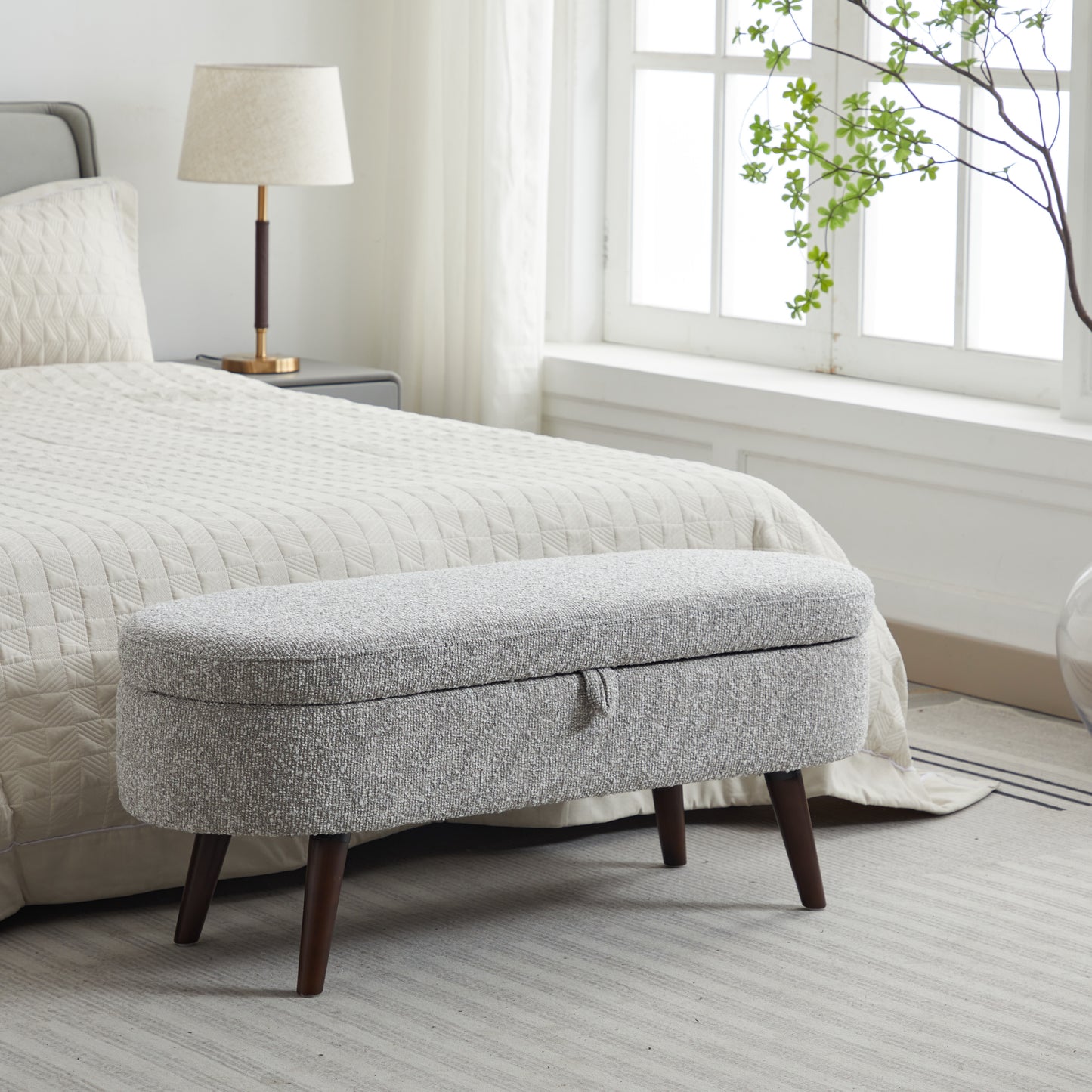 Textured gray storage ottoman with dark wooden legs perfect for bedroom use