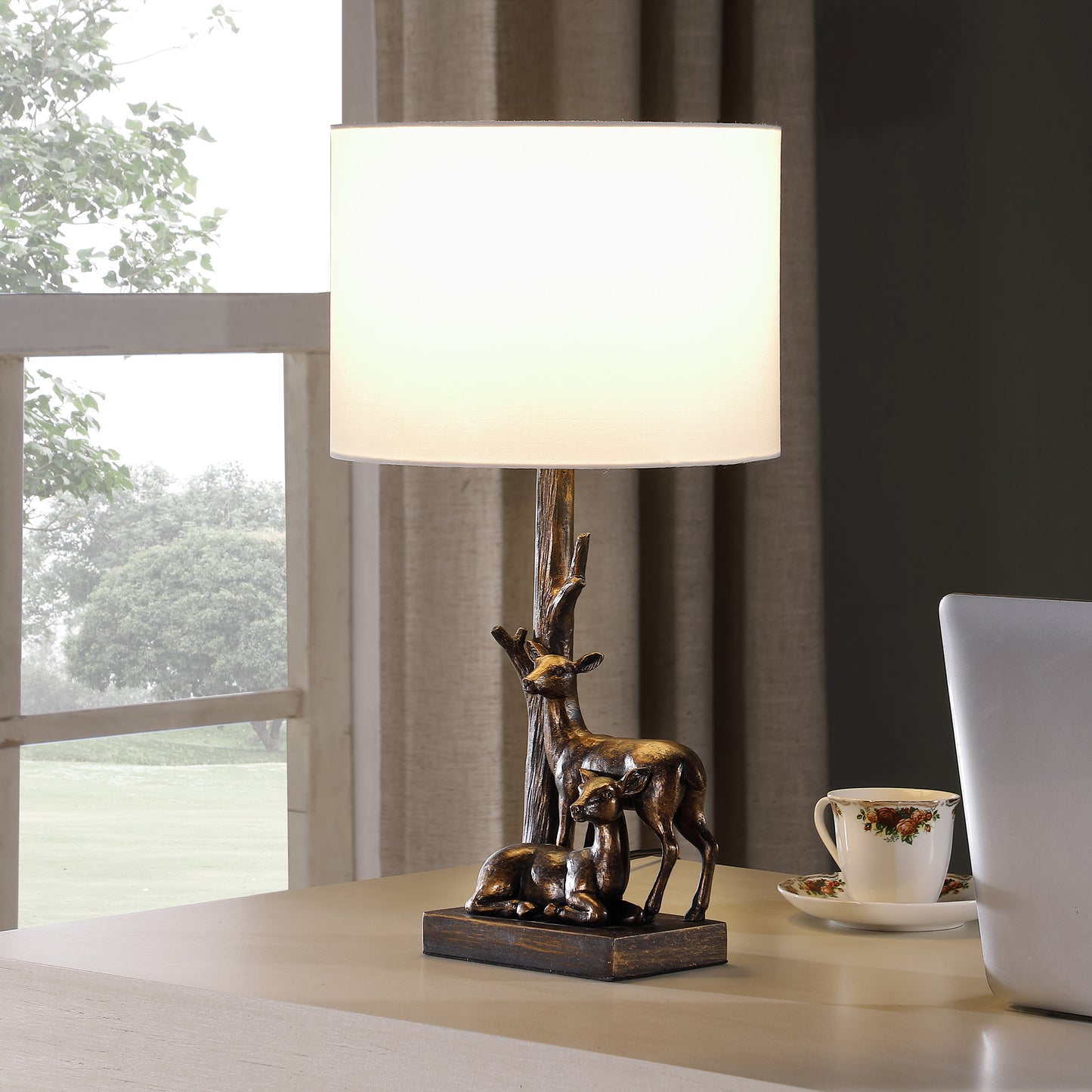 Bronze table lamp with deer figurine base and cream shade for a rustic accent