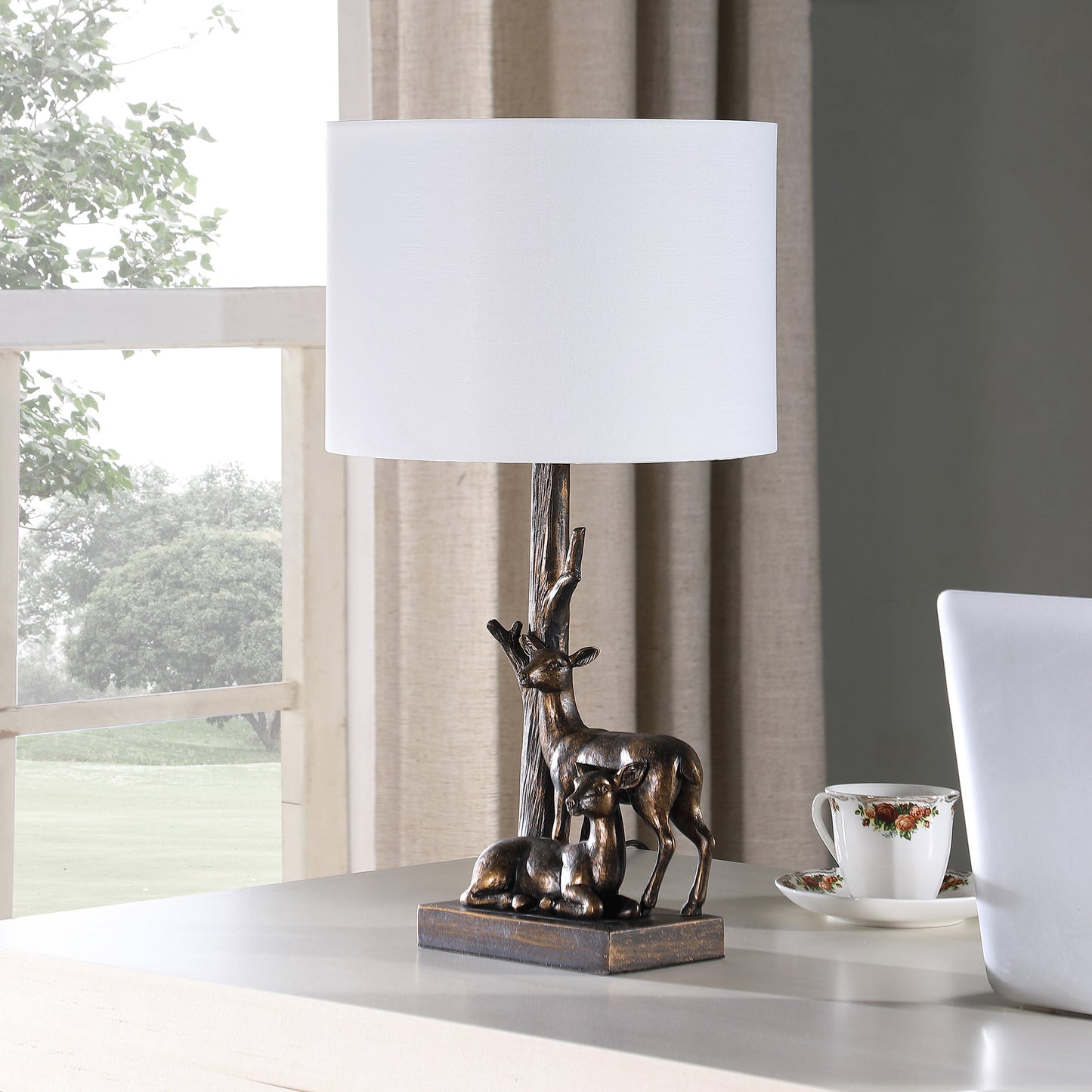Bronze deer table lamp with a white drum shade and a woodland design