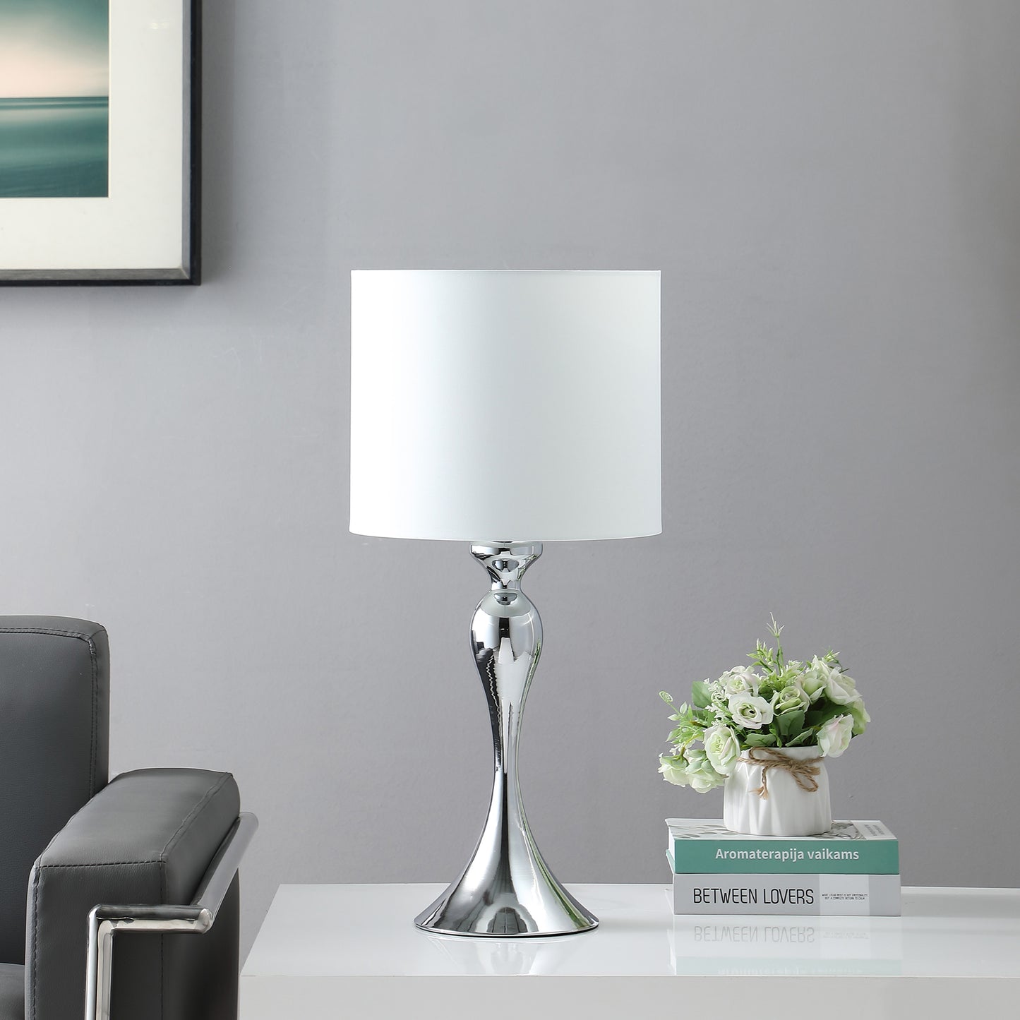 Modern chrome table lamp with a sleek curved base and a white fabric shade perfect for bedside illumination