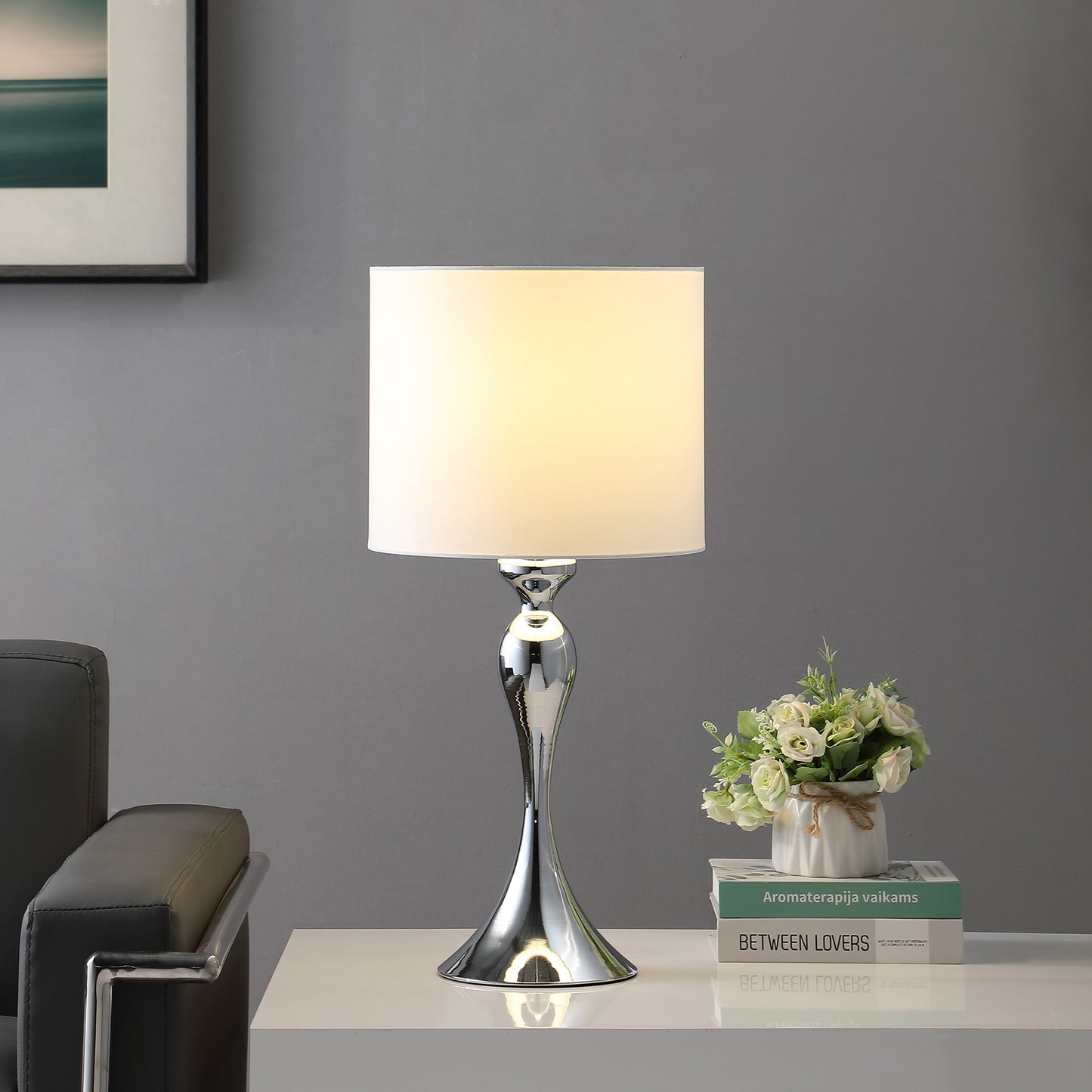 Chrome accent table lamp with a white drum shade ideal for bedside or living room use