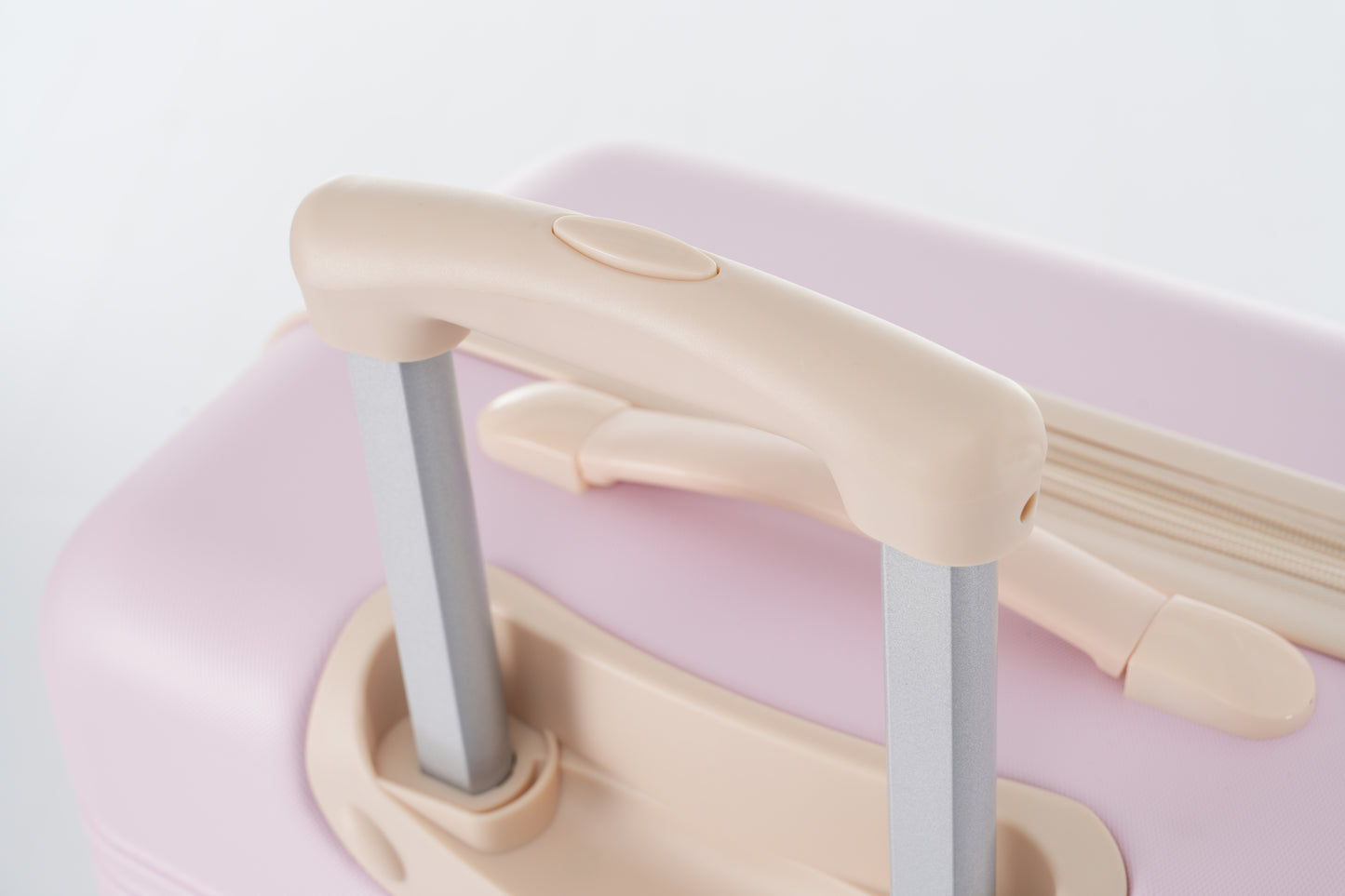 Closeup of a light pink suitcase with a creamcolored retractable handle