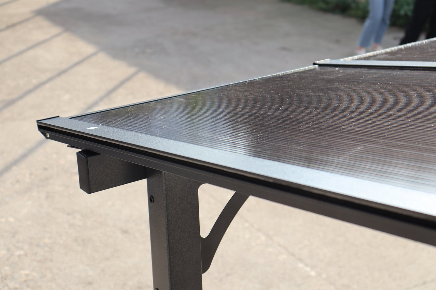 Dark grey polycarbonate table top with ribbed texture and black metal frame