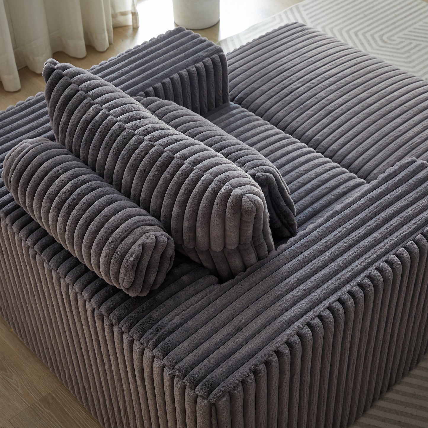 Plush corduroy modular sofa in dark grey featuring comfortable cylinder pillows for ultimate relaxation