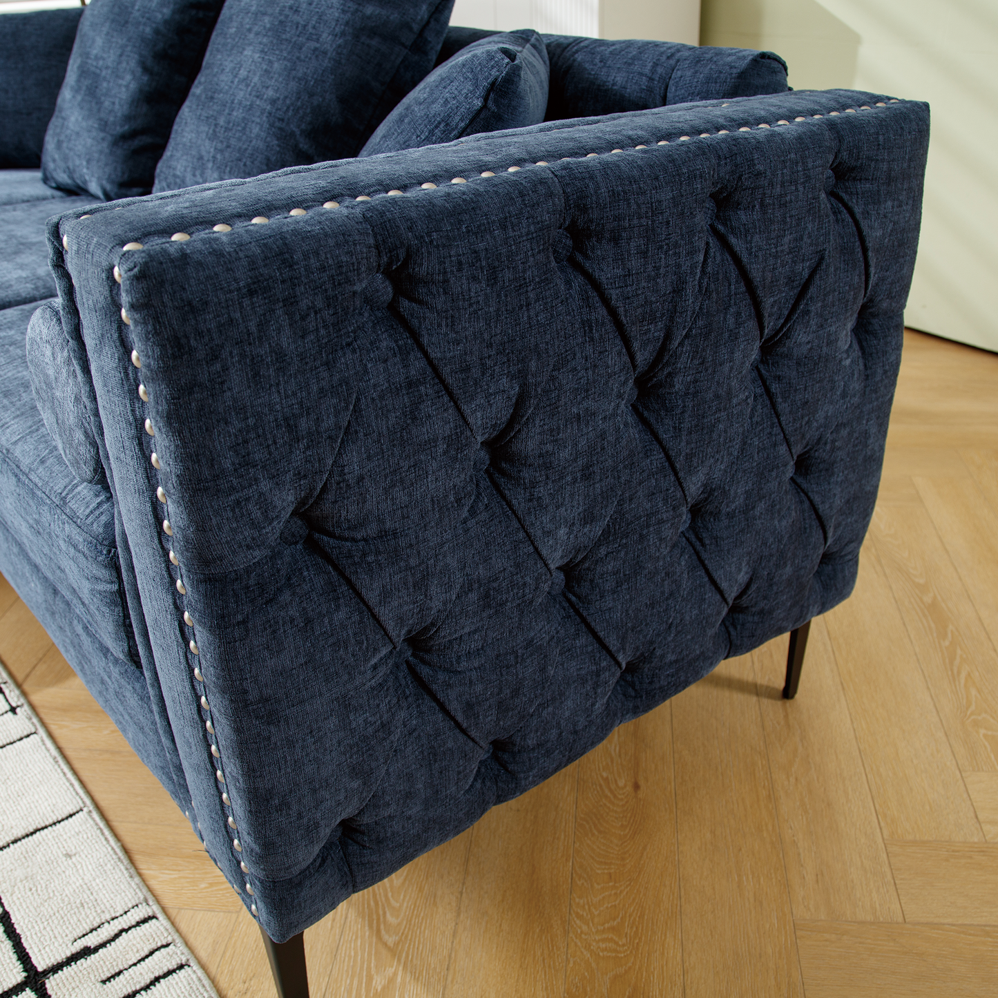 Dark navy upholstered sofa with diamond tufting and nailhead trim details