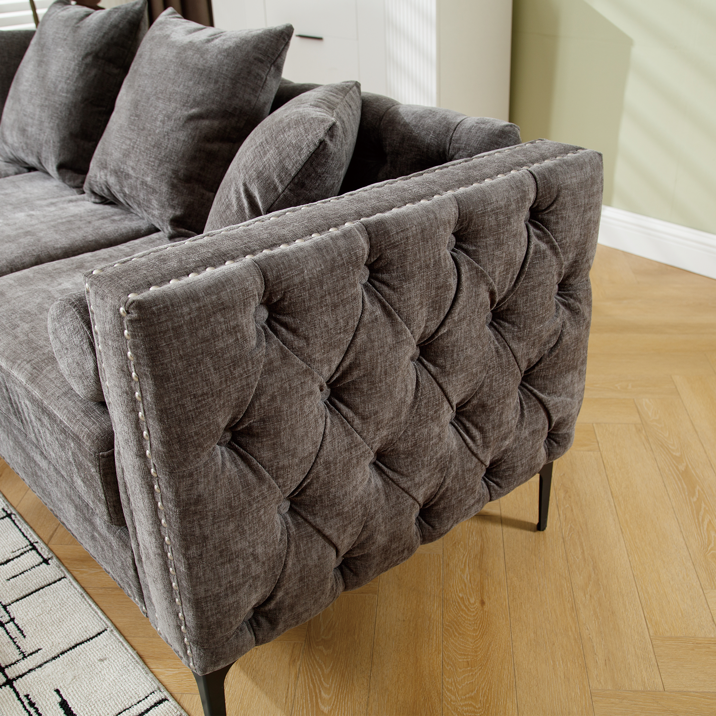 Dark grey upholstered sofa with tufted side and decorative nailhead trim