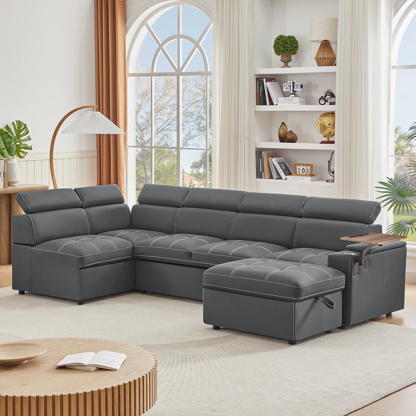 Dark gray sectional sofa with white stitching adjustable headrests and builtin storage ottoman