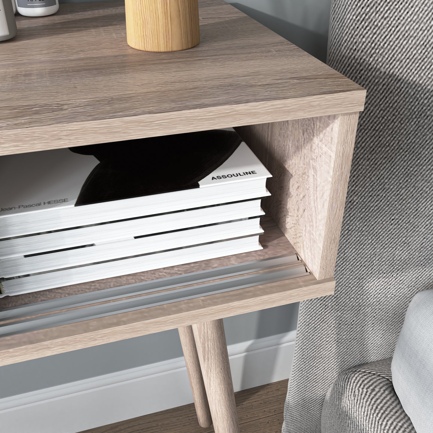 Light oak bedside table with open shelving holding a stack of art books