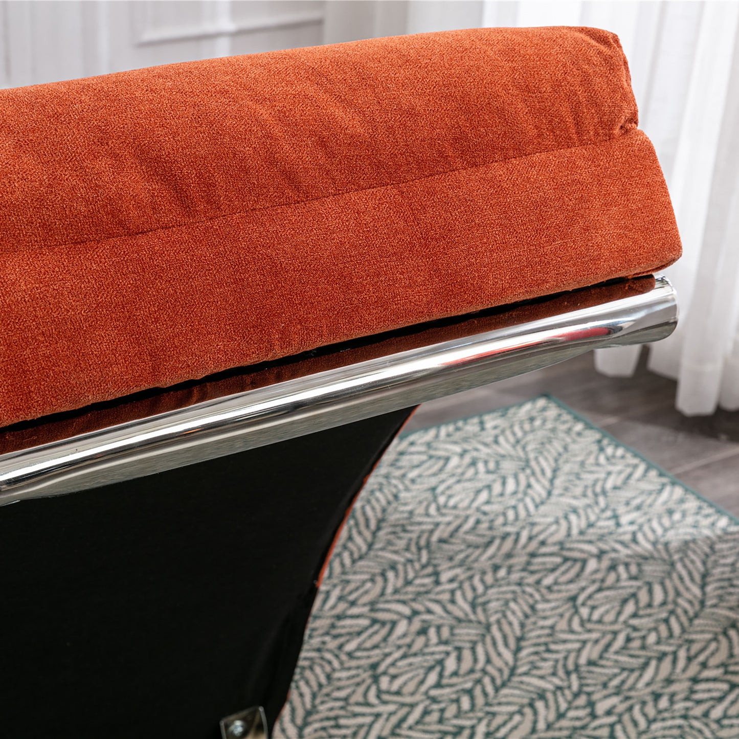 Close up of a plush orange fabric sofa cushion with a chrome accent bar