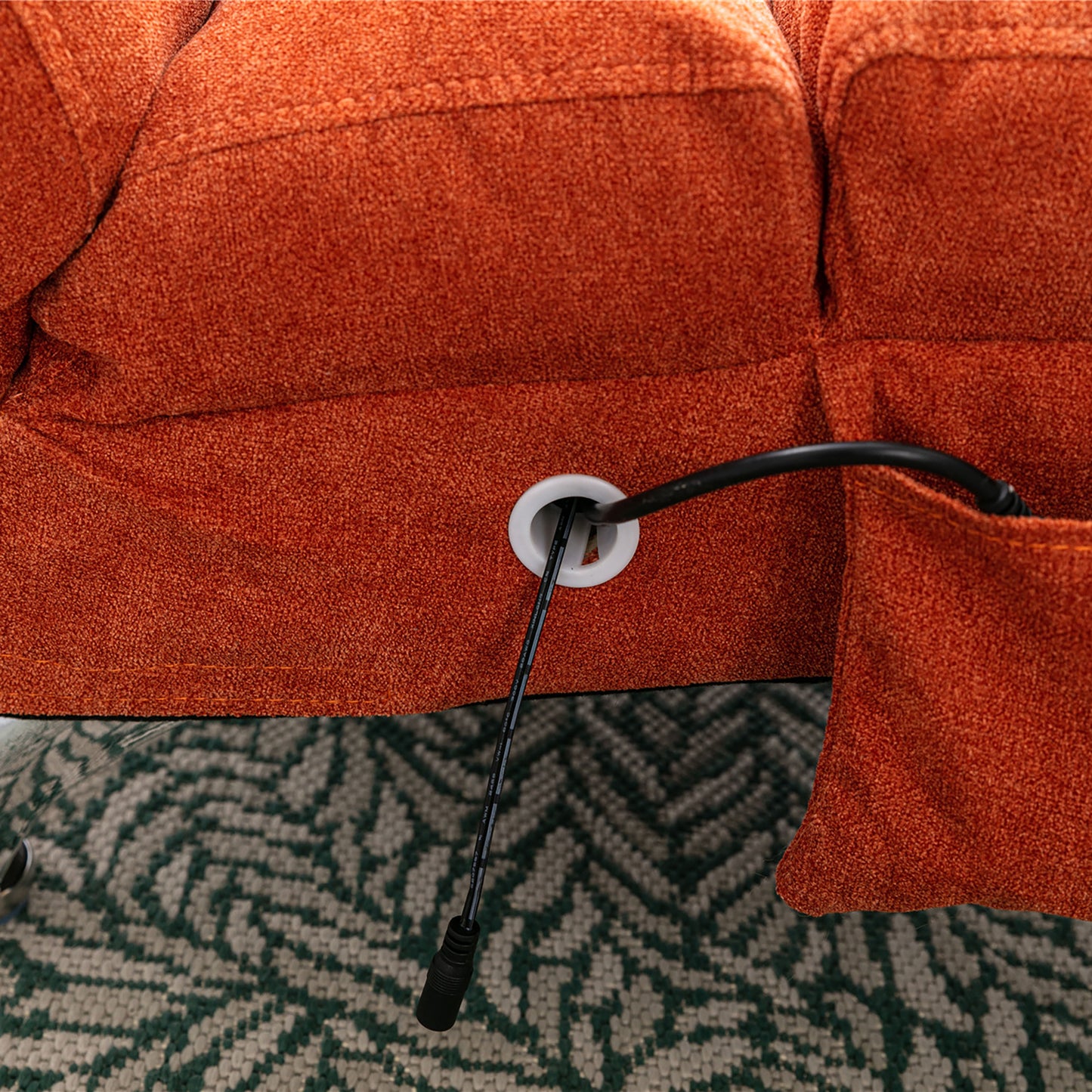 Closeup of orange fabric sofa showing integrated power cord grommet