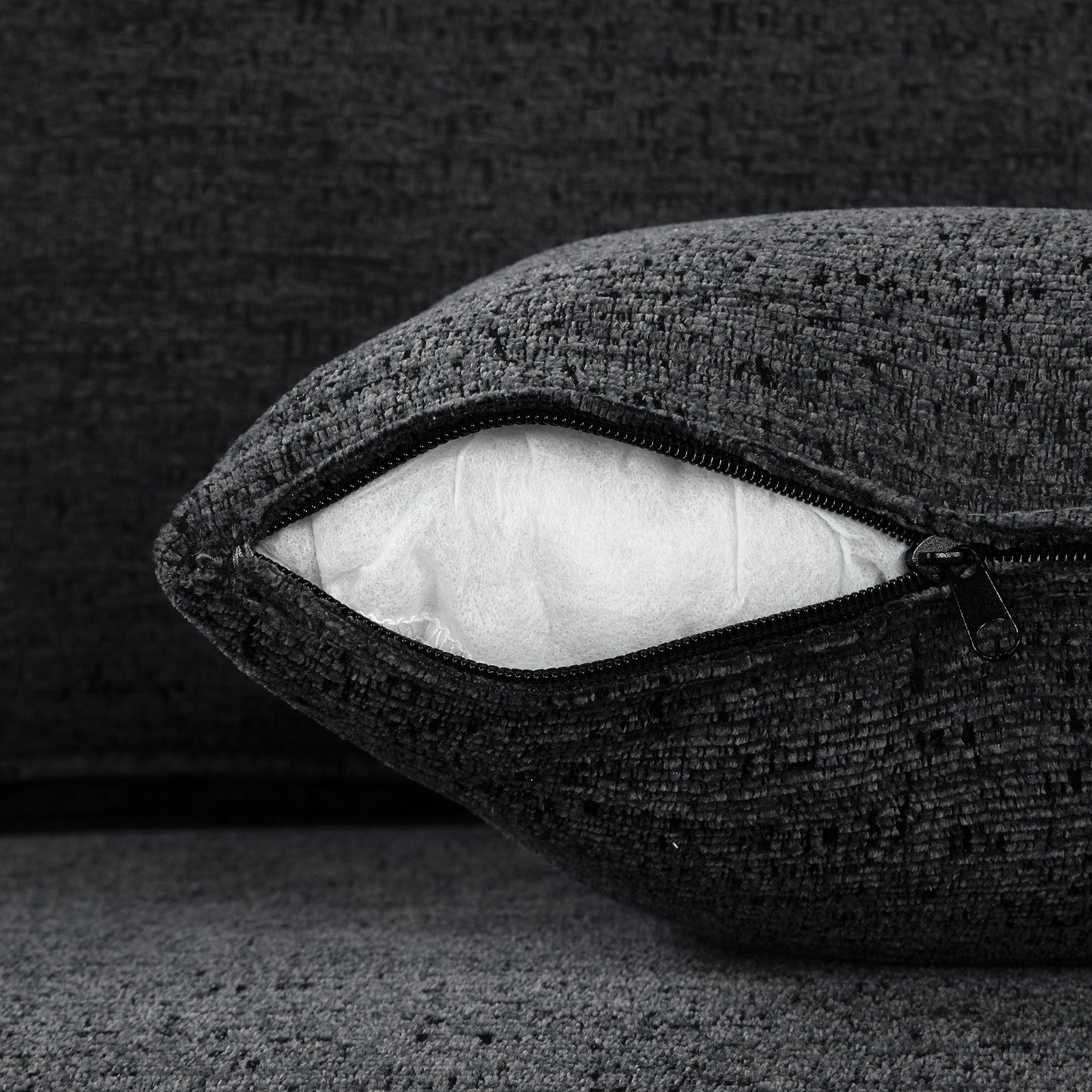 Dark gray textured throw pillow with visible white stuffing and black zipper detail