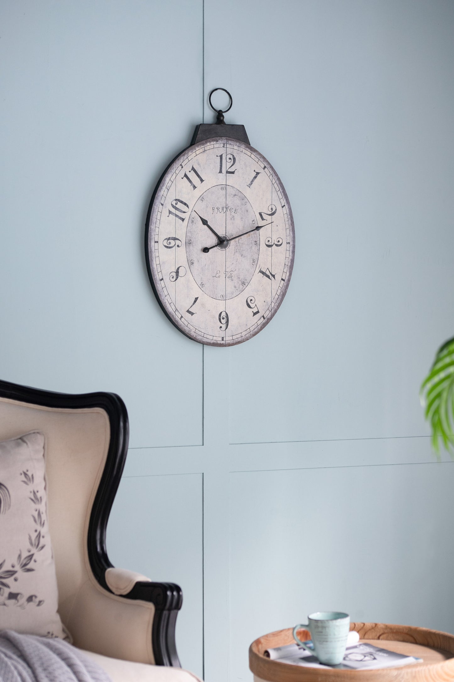 Oval decorative wall clock with vintage French text and distressed finish