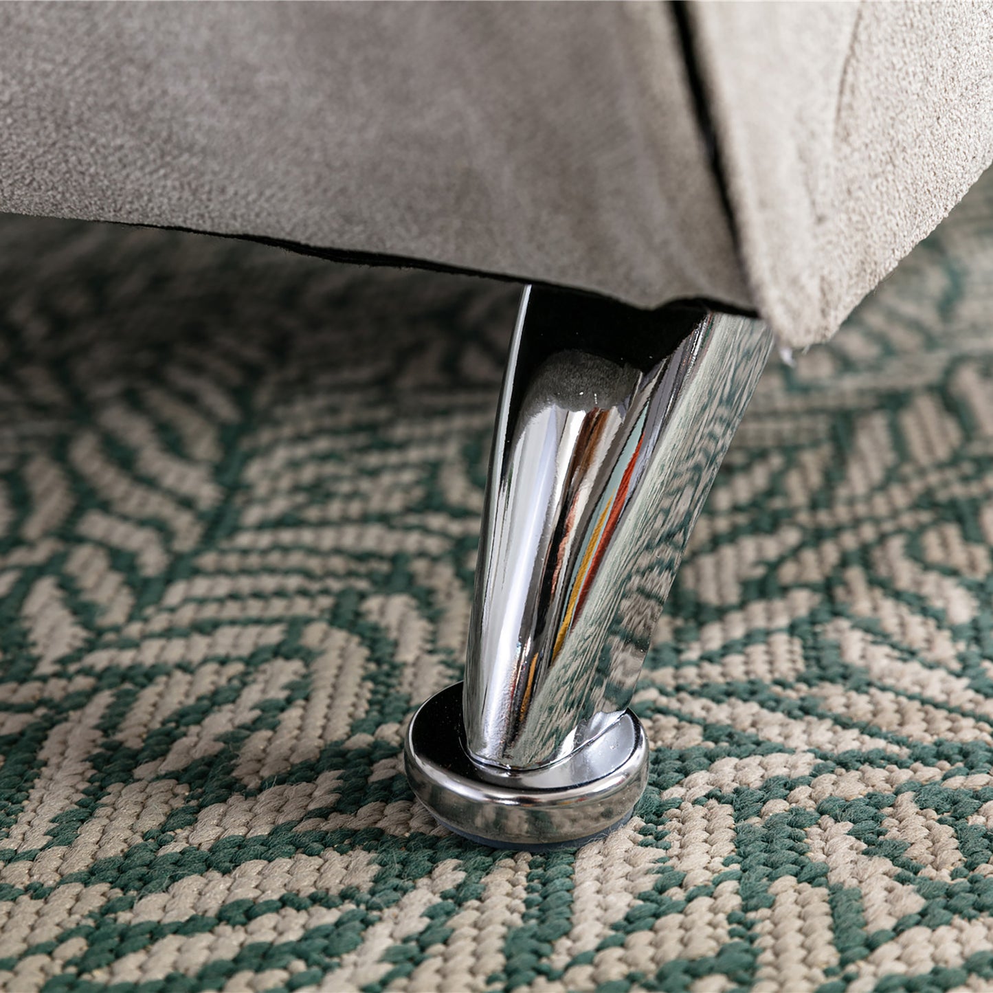 Chrome furniture leg with clear protector pad on patterned rug