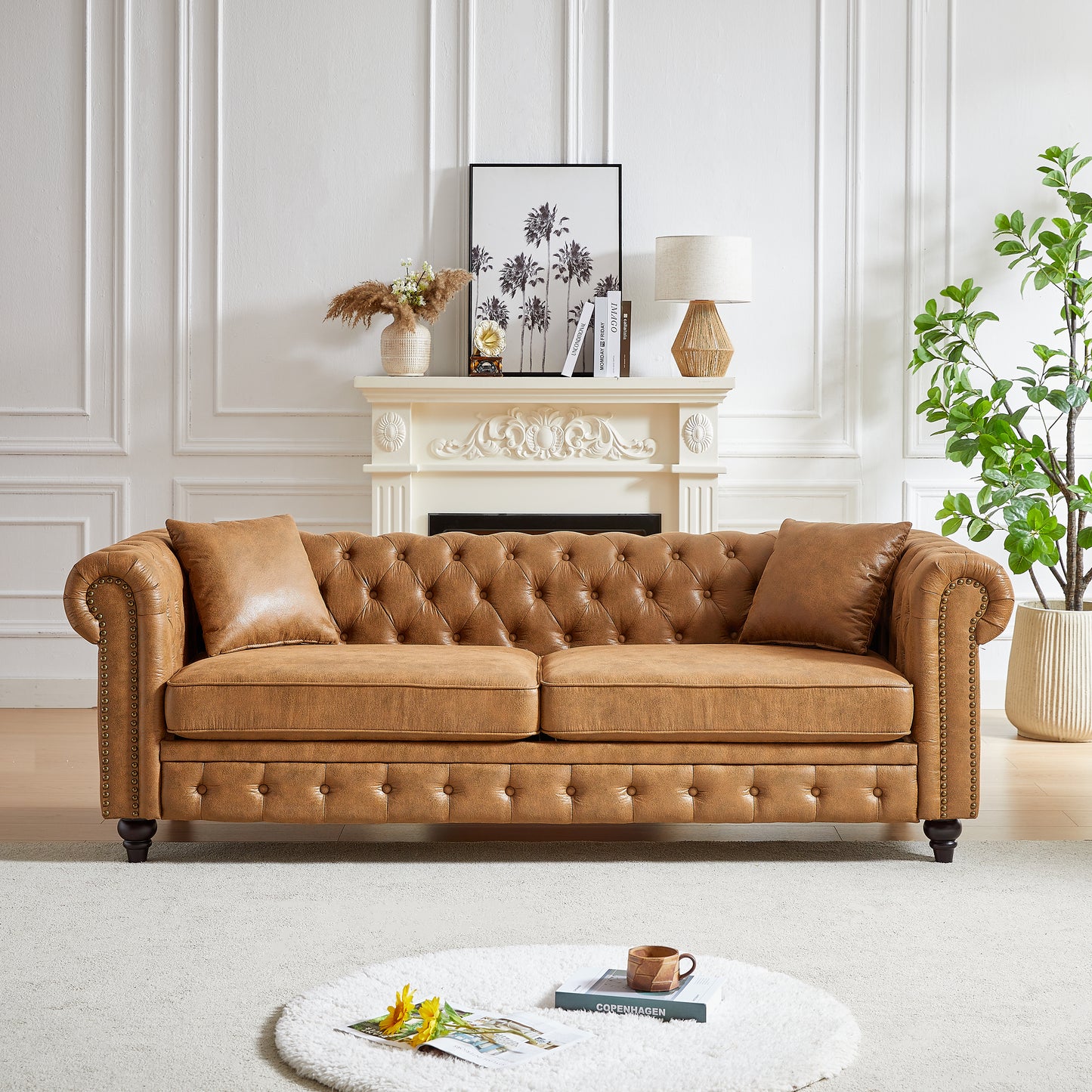 Tufted tan leather chesterfield sofa with silver nailhead trim and matching throw pillows