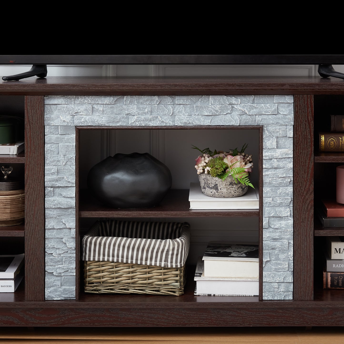 Dark wood TV stand with gray stone fireplace facade and open shelving