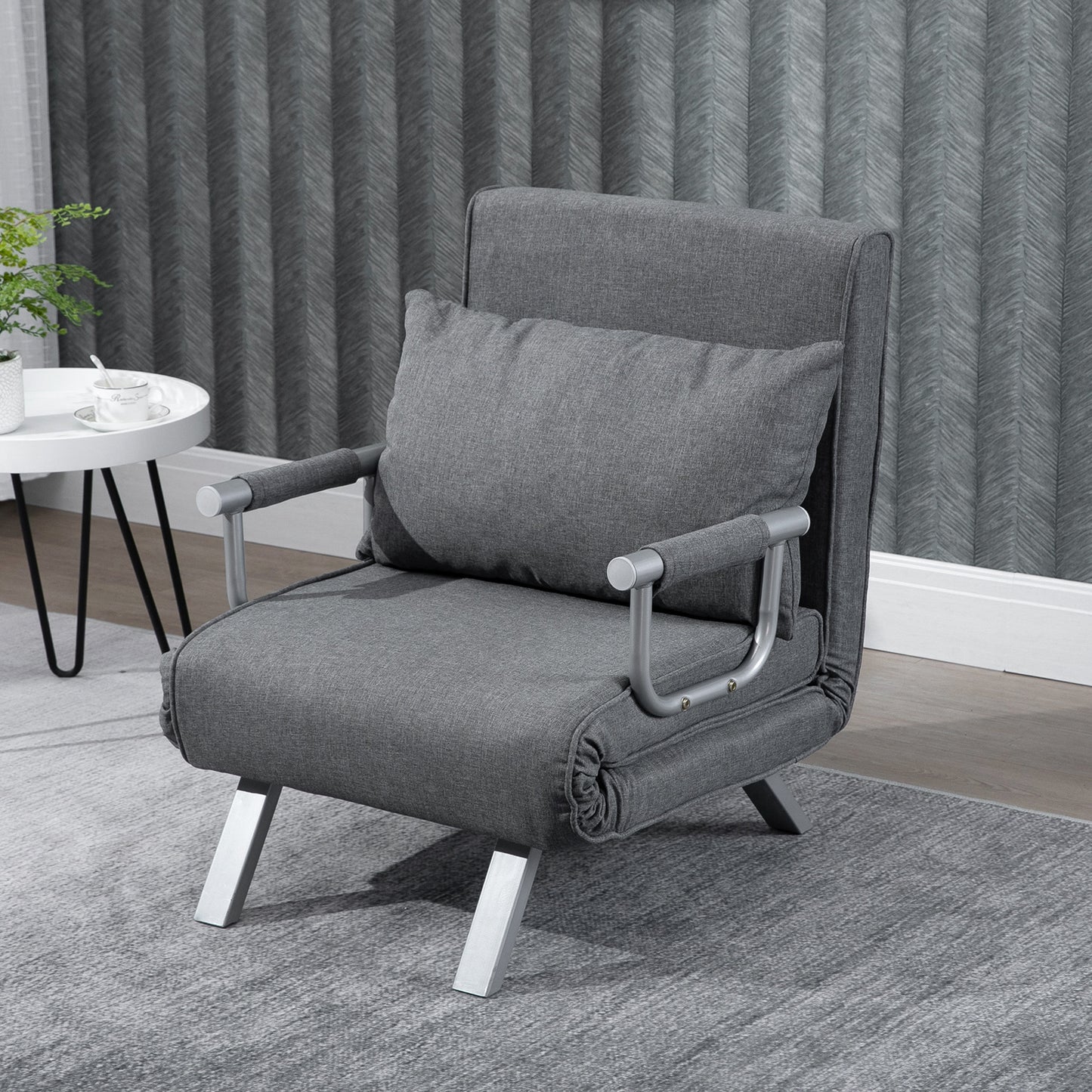 Grey upholstered convertible armchair with silver metal legs and accent pillow