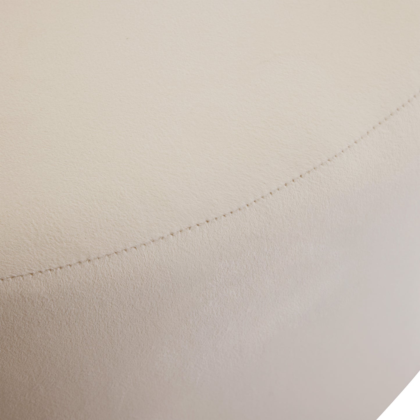 Closeup of a stitched seam on a textured light beige faux leather ottoman