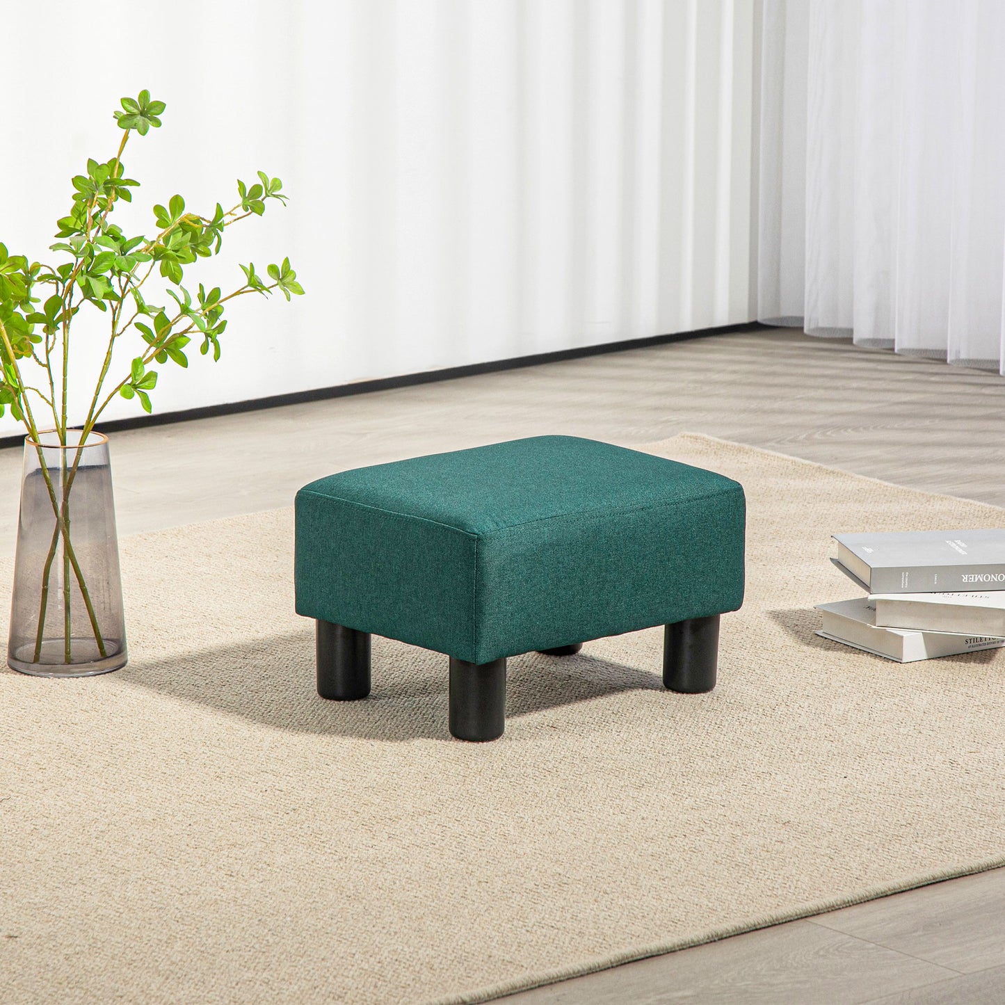 Square teal fabric ottoman with dark wooden legs on a beige rug