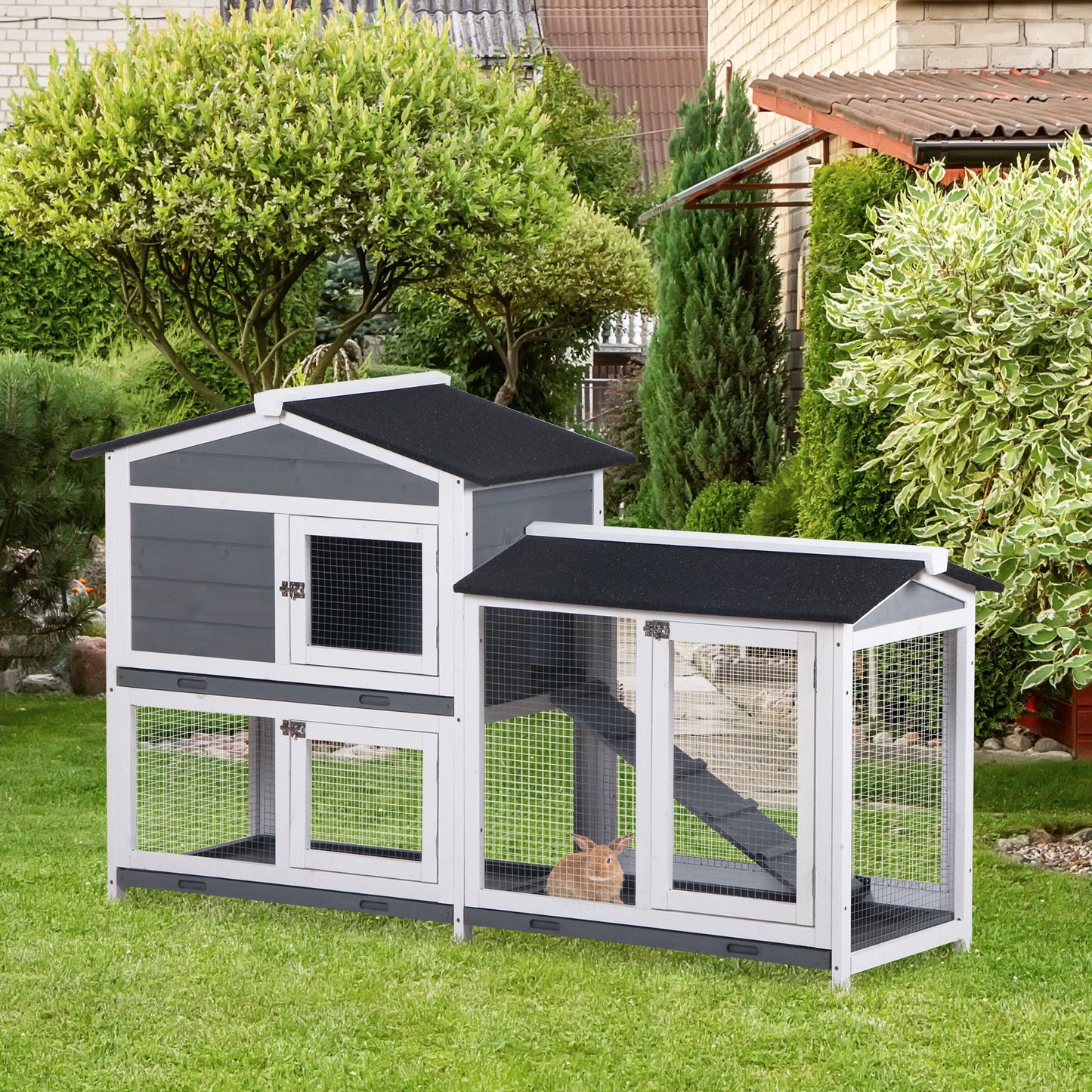 Twotier grey and white wooden rabbit hutch with wire mesh doors and a ramp set on a green lawn