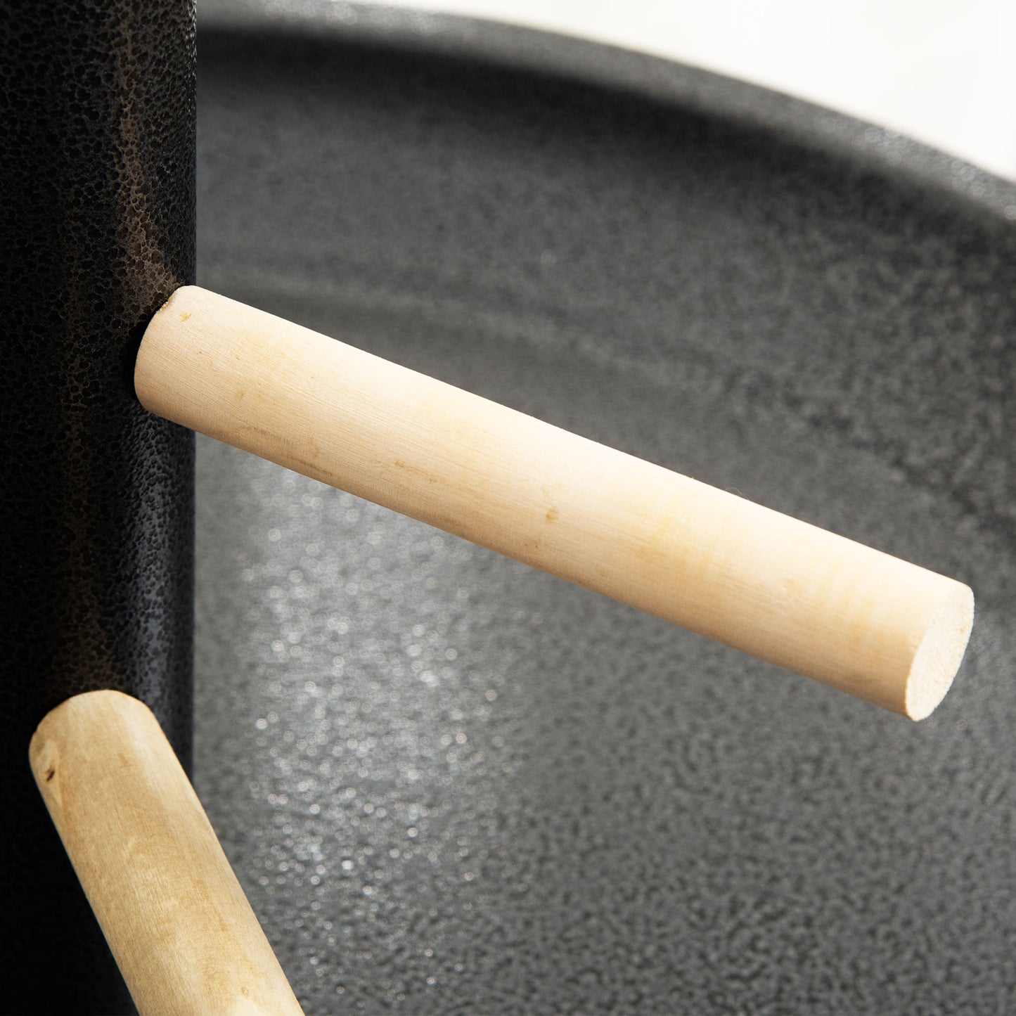 Black textured surface with a natural wood handle for a portable grill
