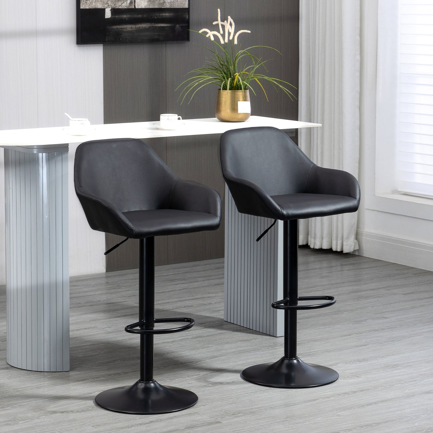 Two black faux leather bar stools with adjustable height and footrests