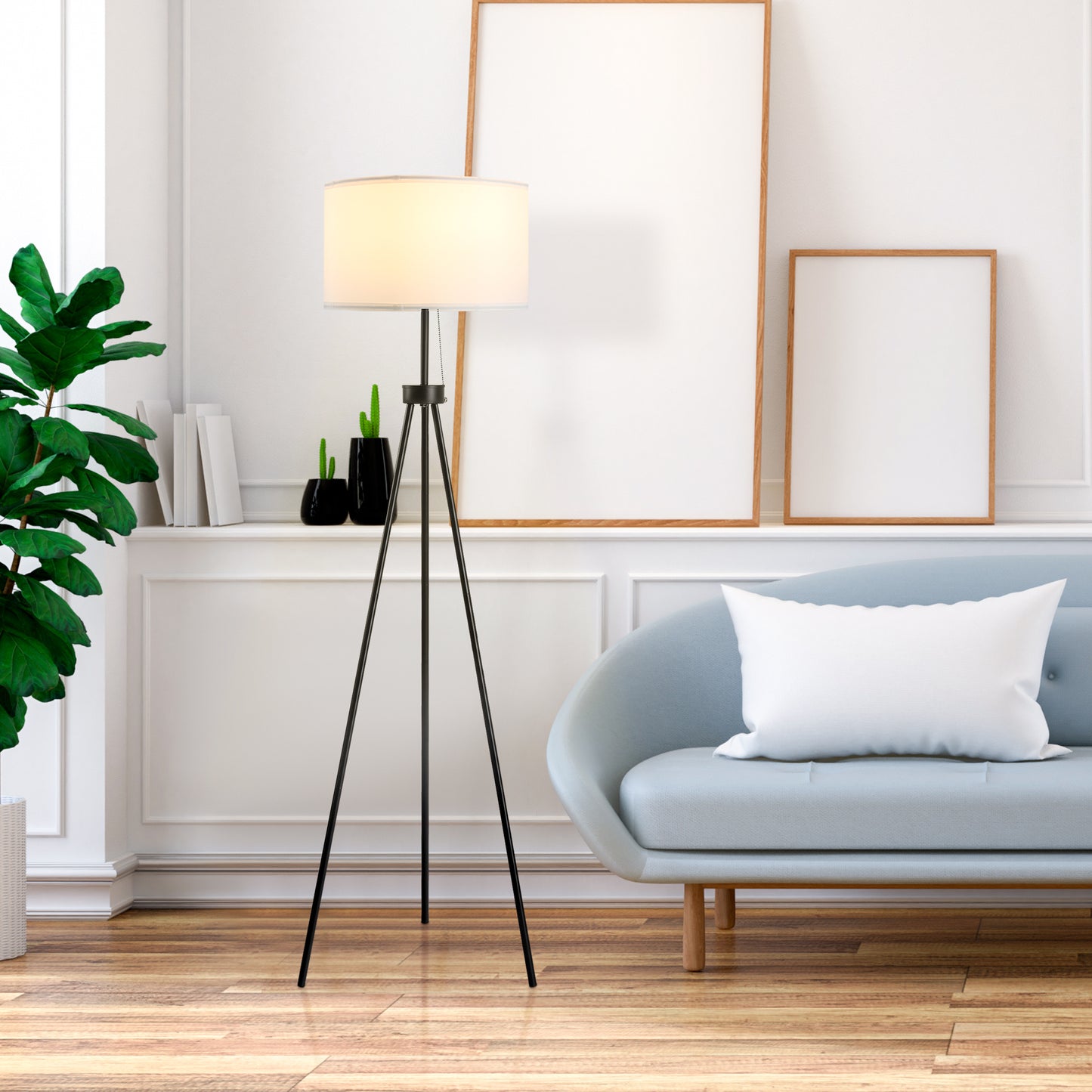 Modern black metal tripod floor lamp with a white fabric shade illuminating a living room