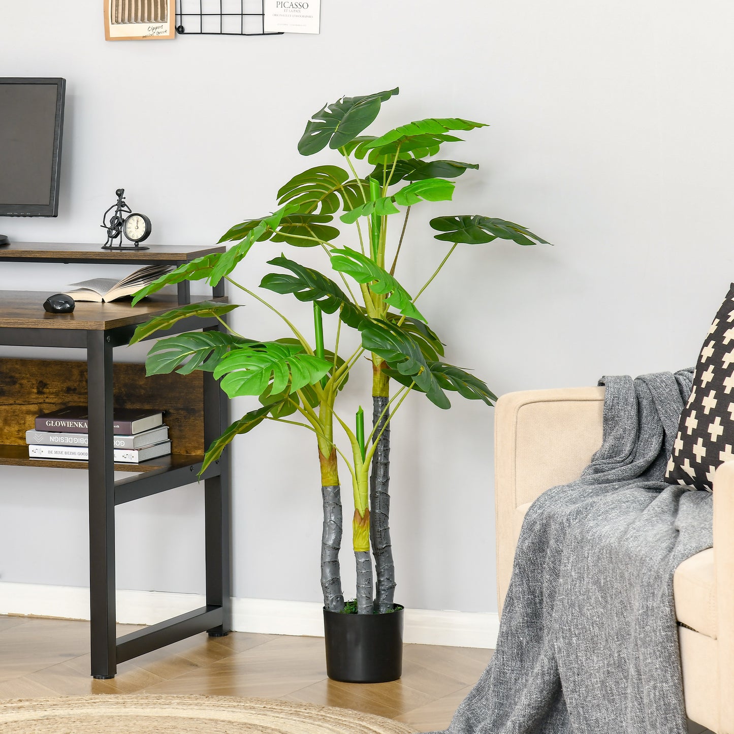 Large artificial Monstera plant with dark green split leaves in a black pot