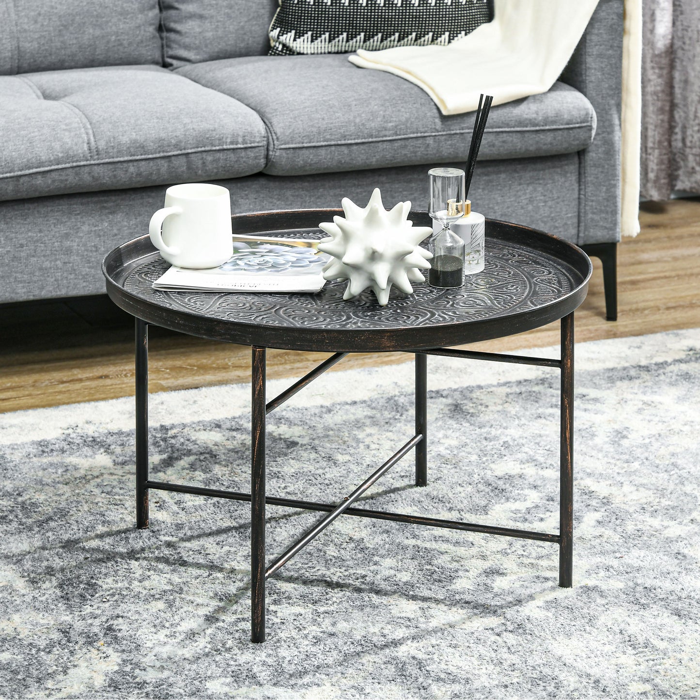 Antique brass round coffee table with embossed metal top and black legs