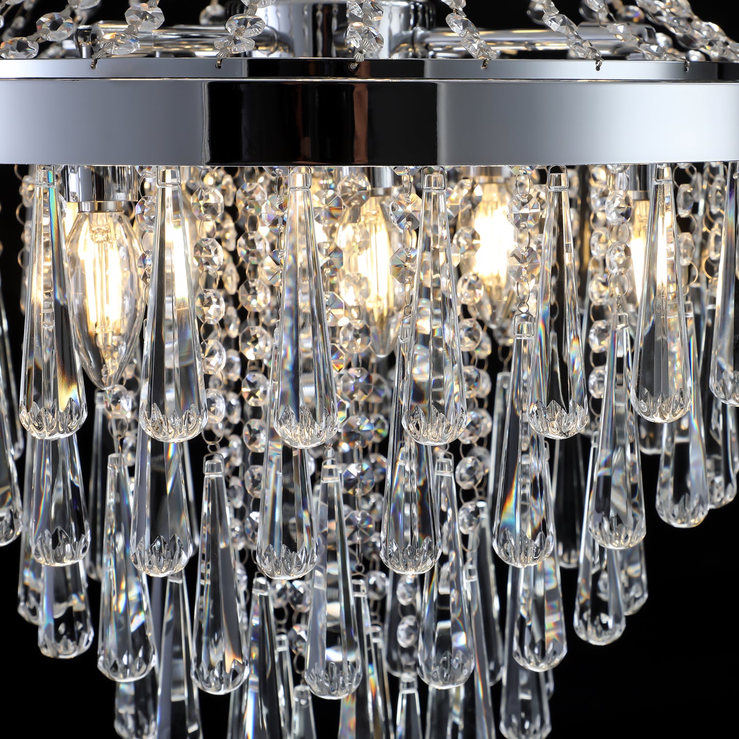 Close up of a modern crystal chandelier with teardrop prisms and chrome accents