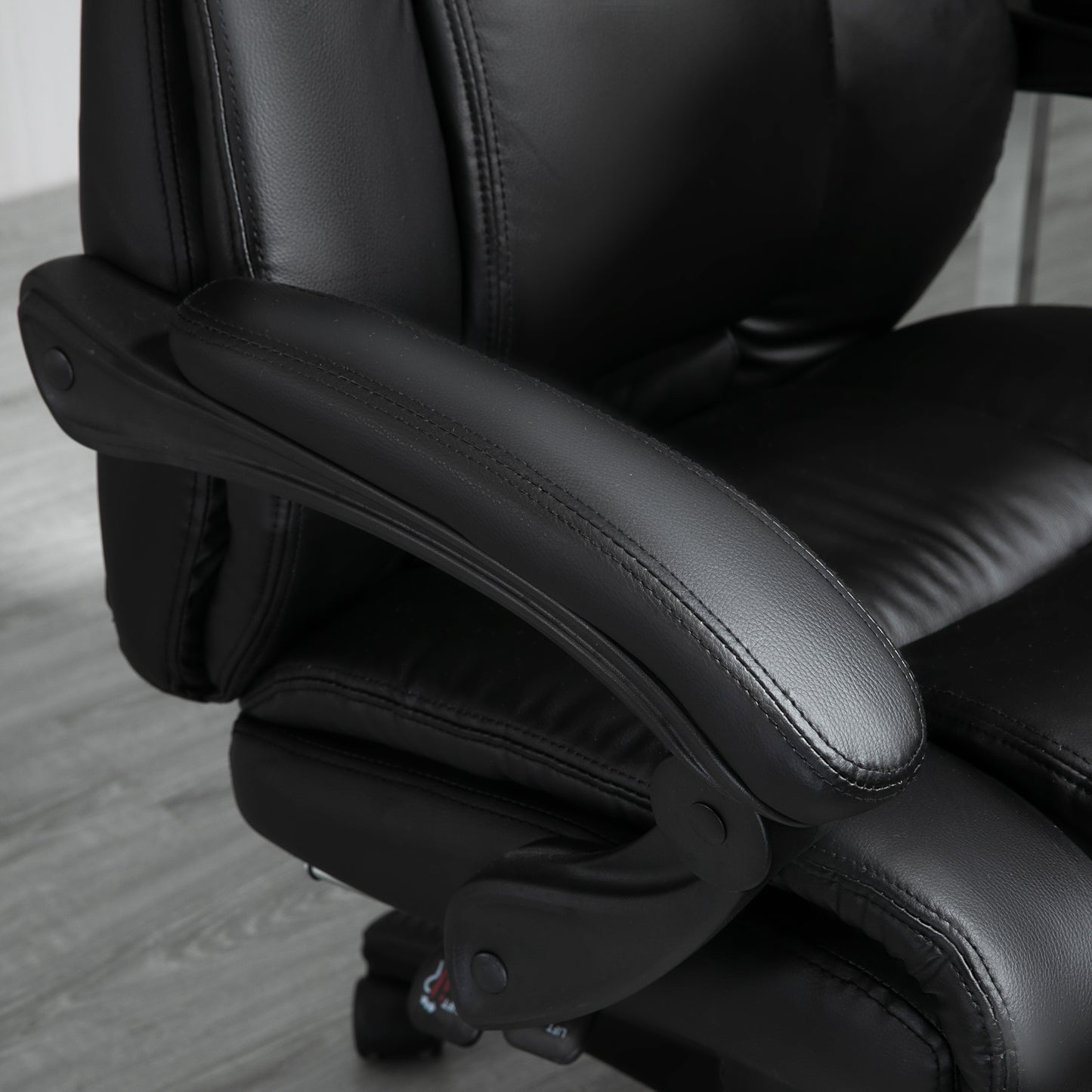 Closeup of black faux leather office chair armrest with detailed stitching