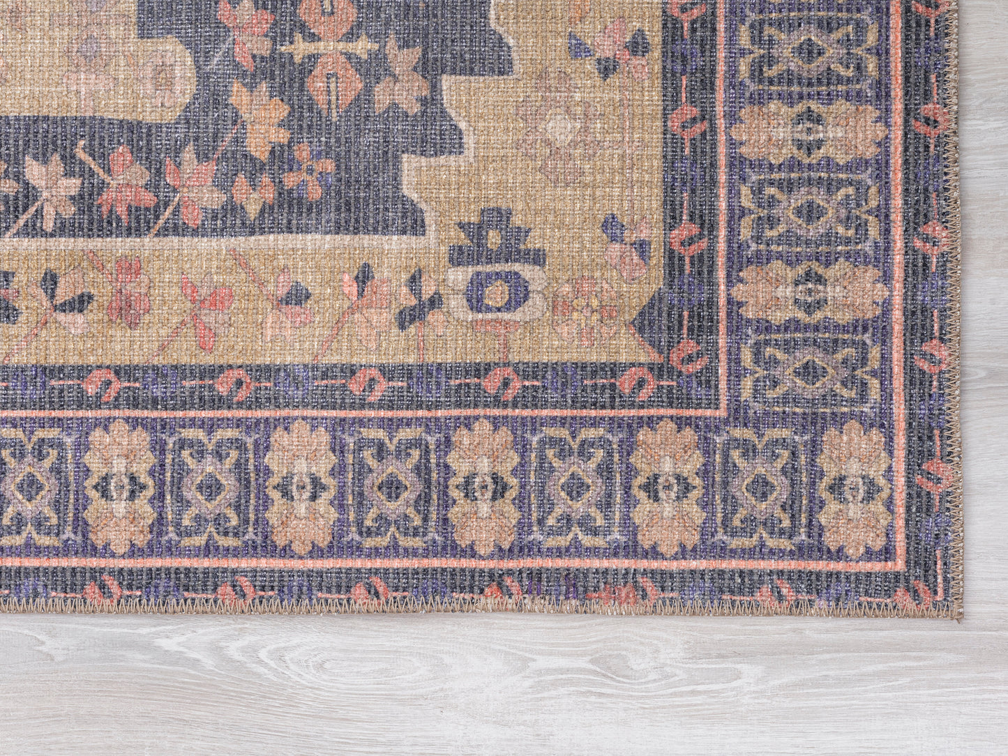 Traditional Persian rug with intricate floral patterns in navy gold and muted coral hues