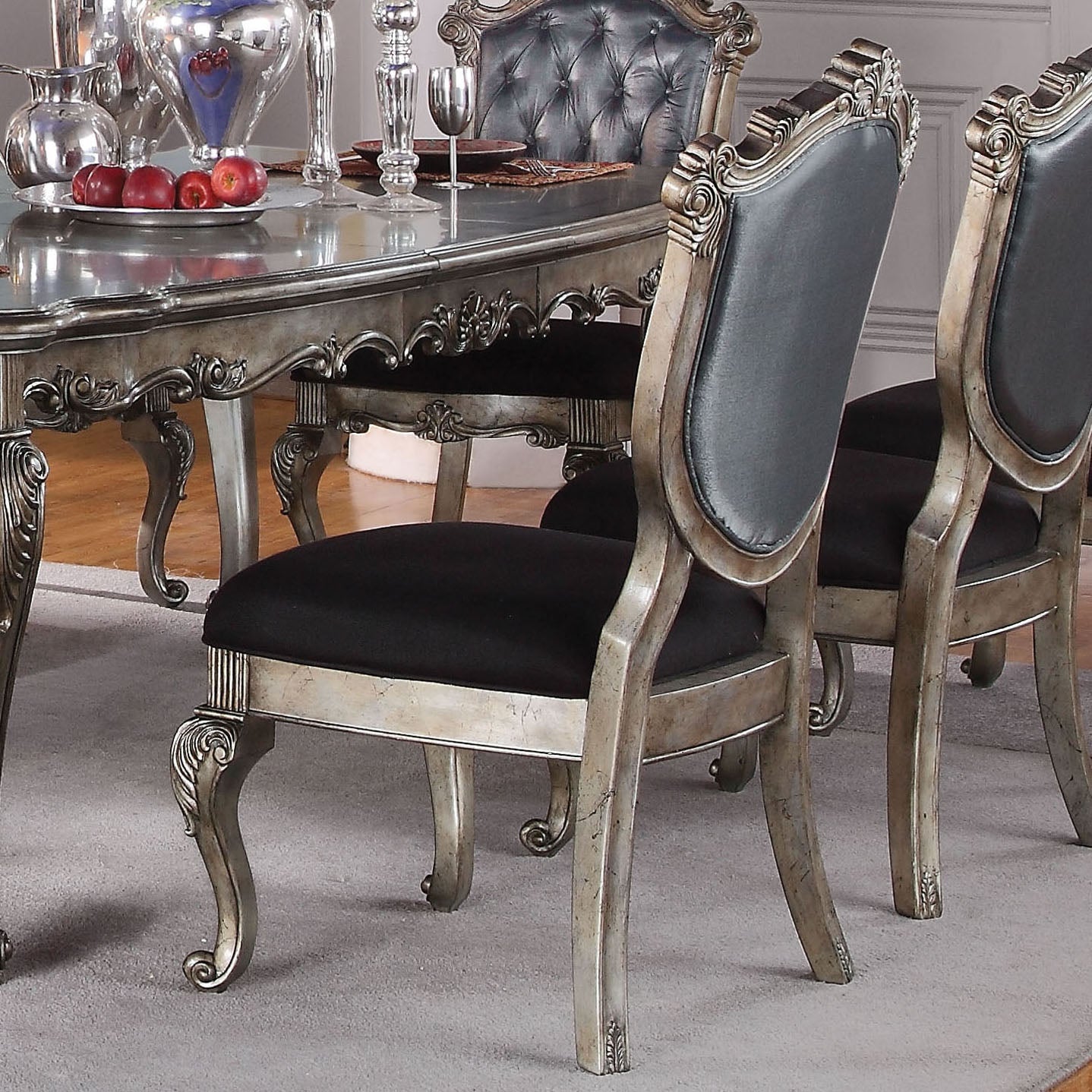 Ornate antique silver dining chair with tufted black leather back and seat