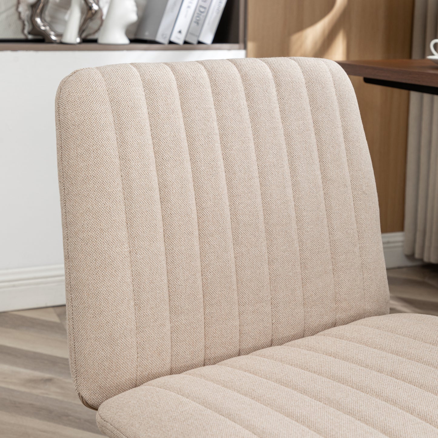 Closeup of a beige linen upholstered dining chair with vertical channel tufting