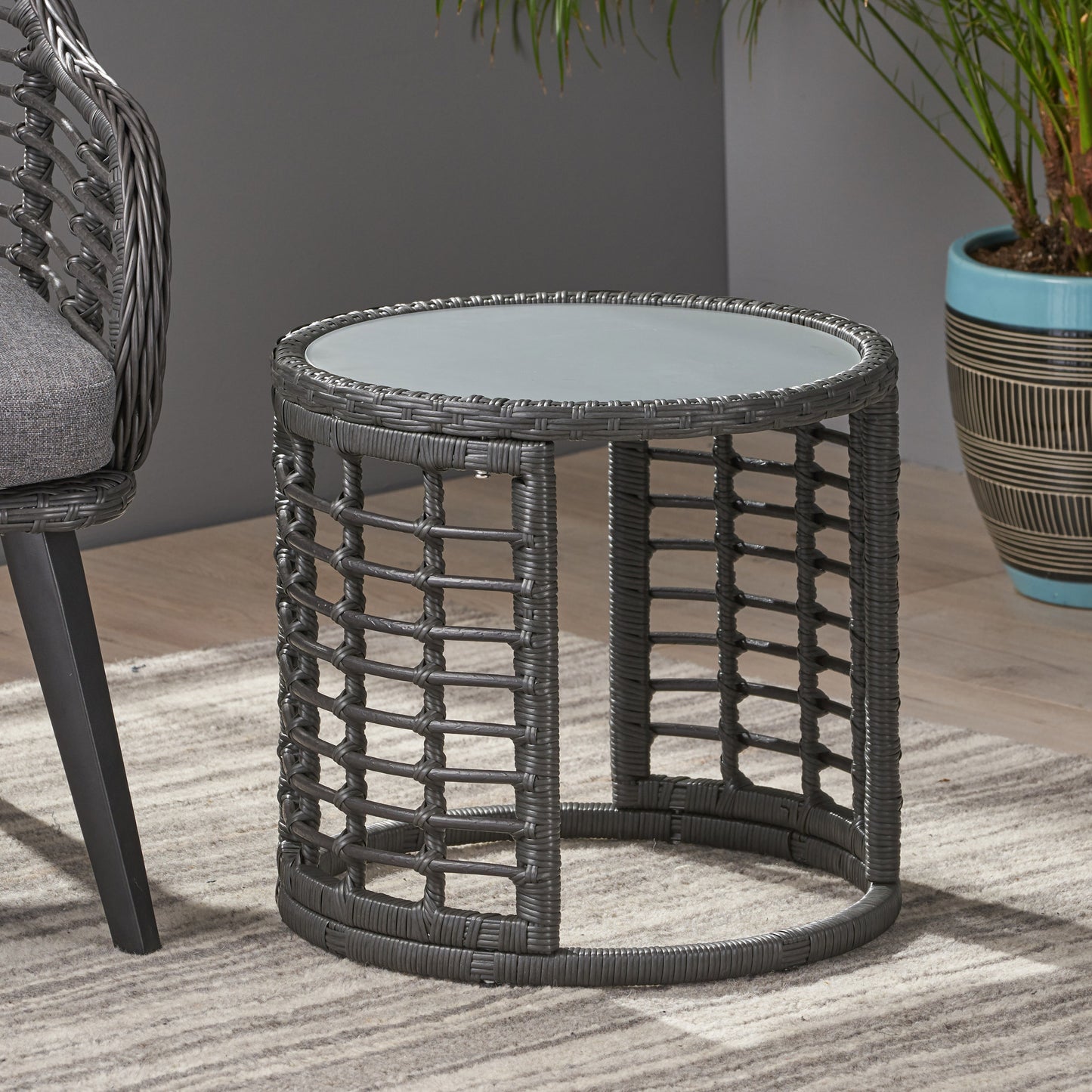 Round grey wicker side table with a glass top perfect for patio use