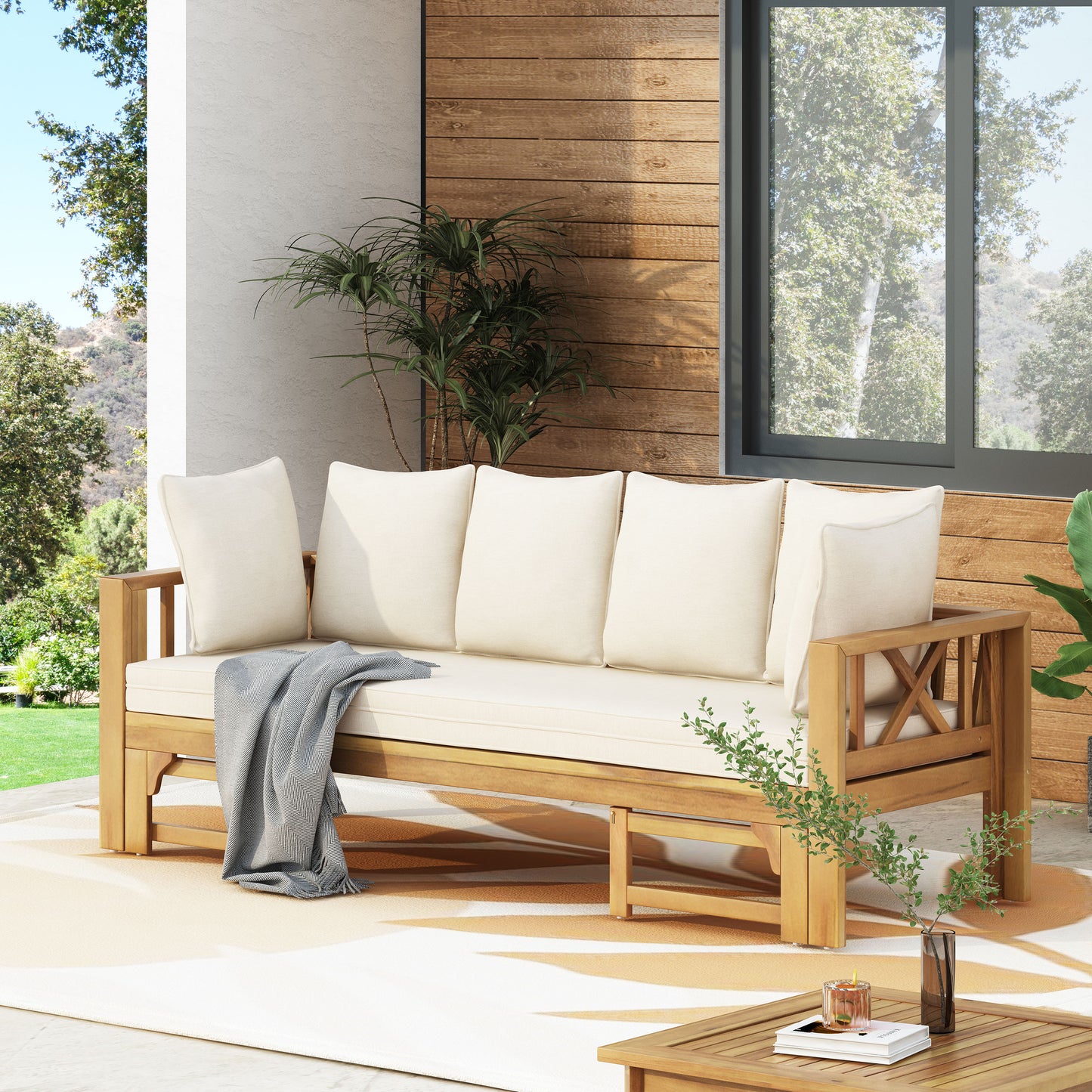 Wooden outdoor sofa with cream cushions and grey throw blanket