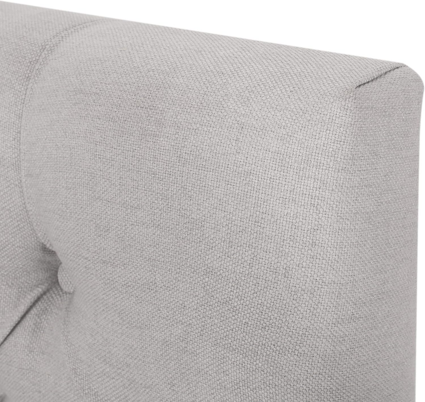 Closeup of light grey textured upholstered headboard with button tufting detail