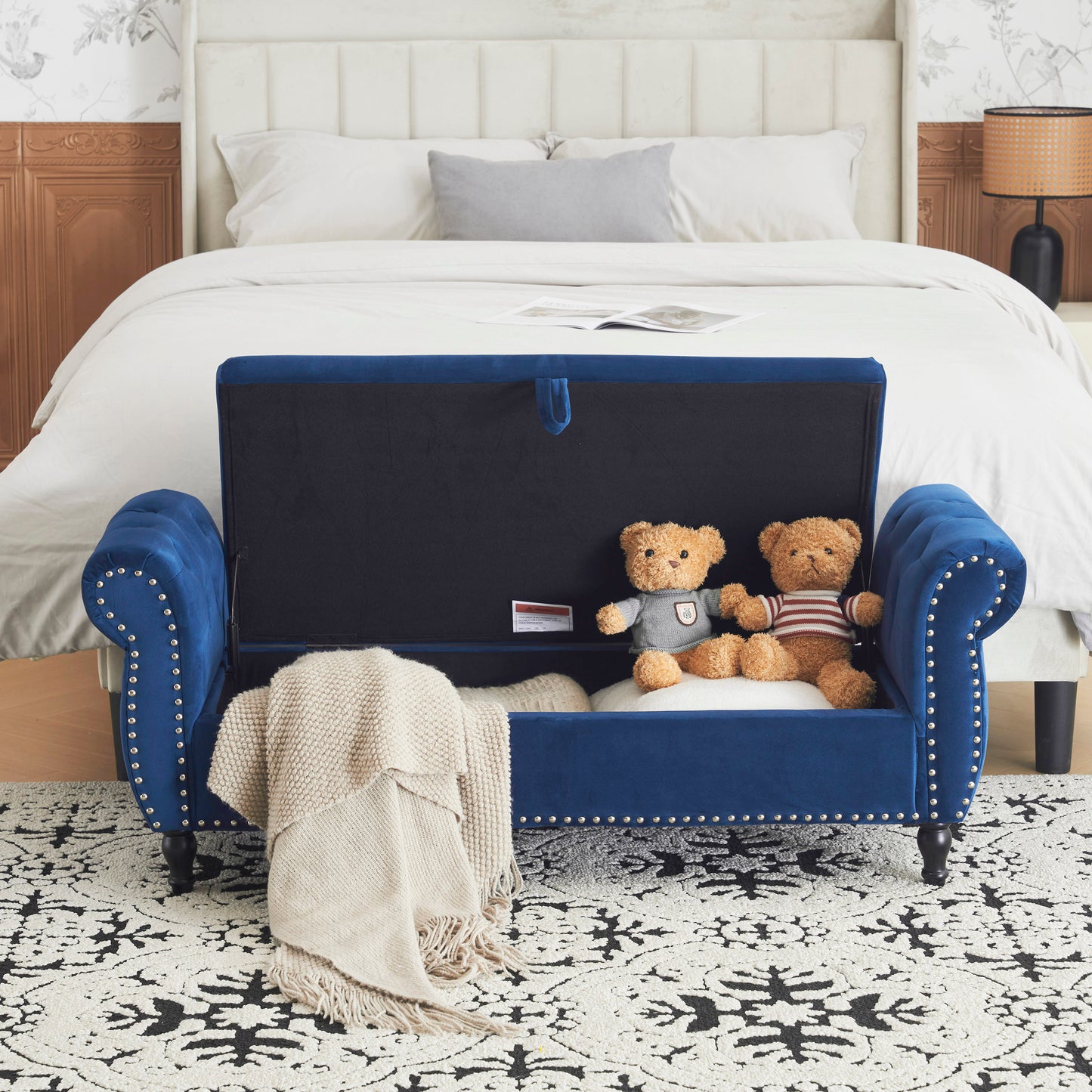 Blue velvet tufted storage bench with silver nailhead trim and open lid revealing teddy bears